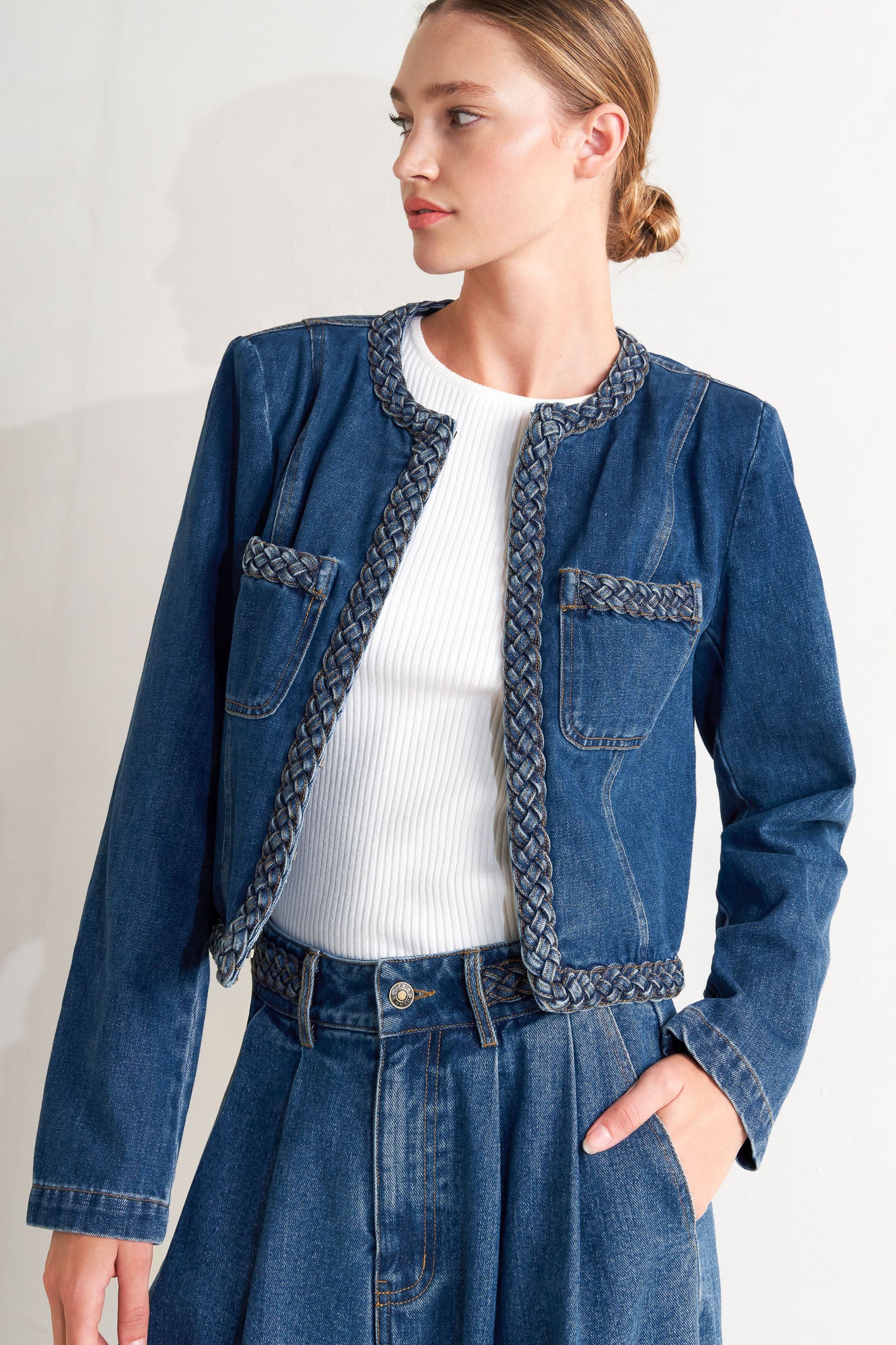A washed denim jacket featuring round neckline, braided trim and hook & eye closure