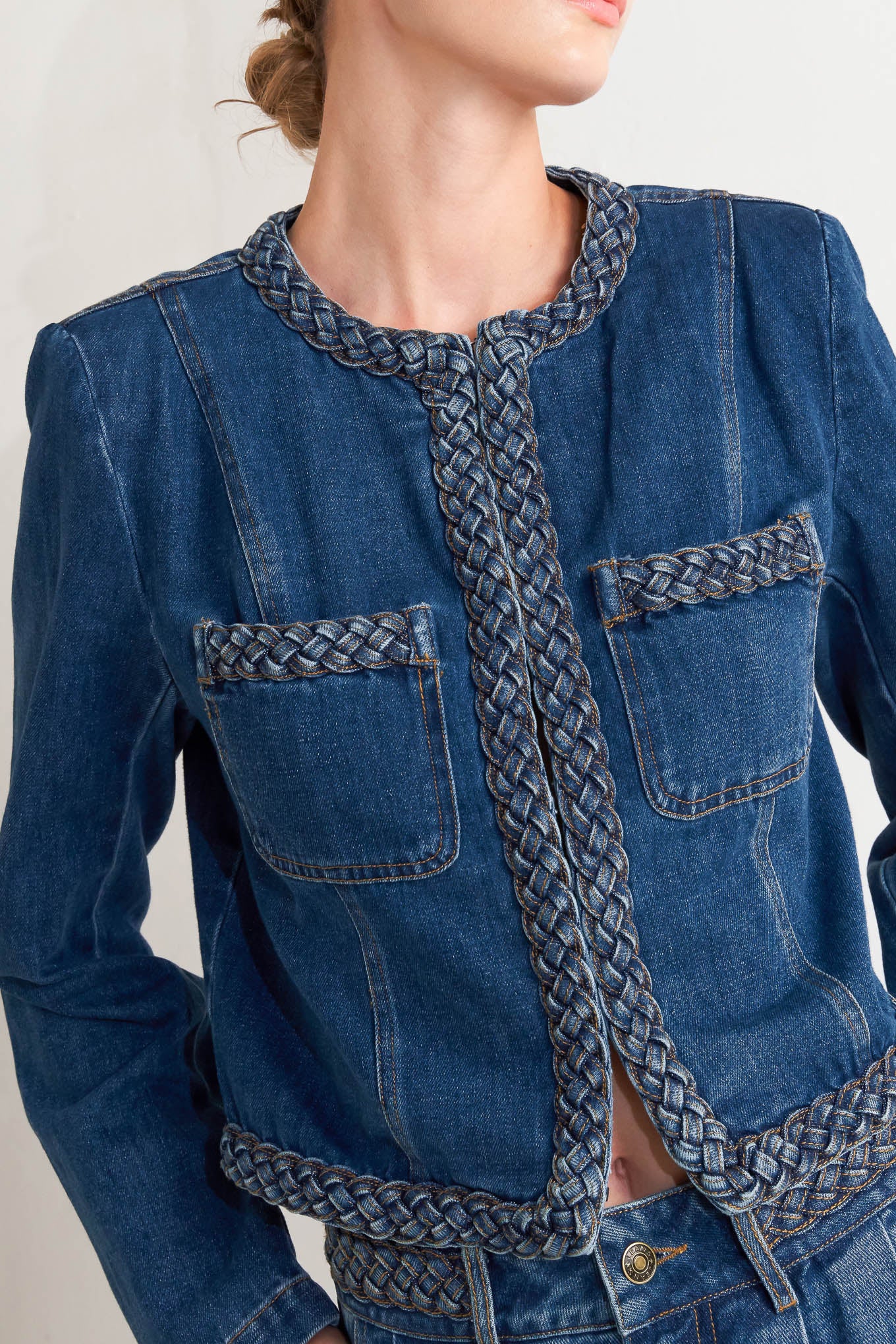 A washed denim jacket featuring round neckline, braided trim and hook & eye closure