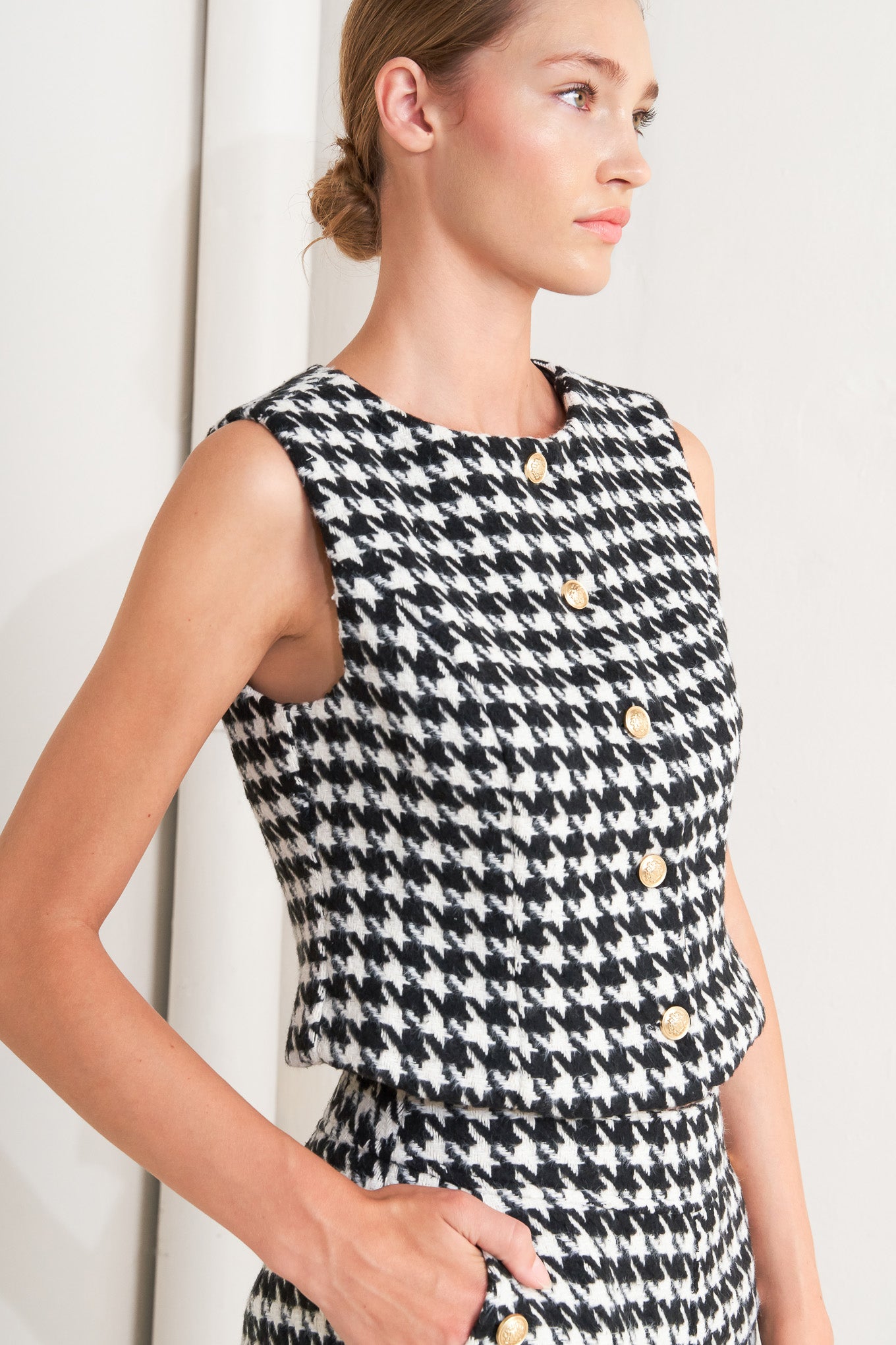 A woven houndstooth vest featuring round neckline, sleeveless and front button down.
