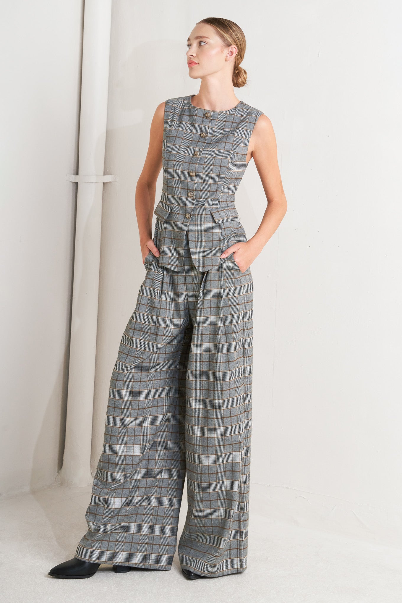 A plaid woven vest featuring round neckline, sleeveless, front button down and side pocket.