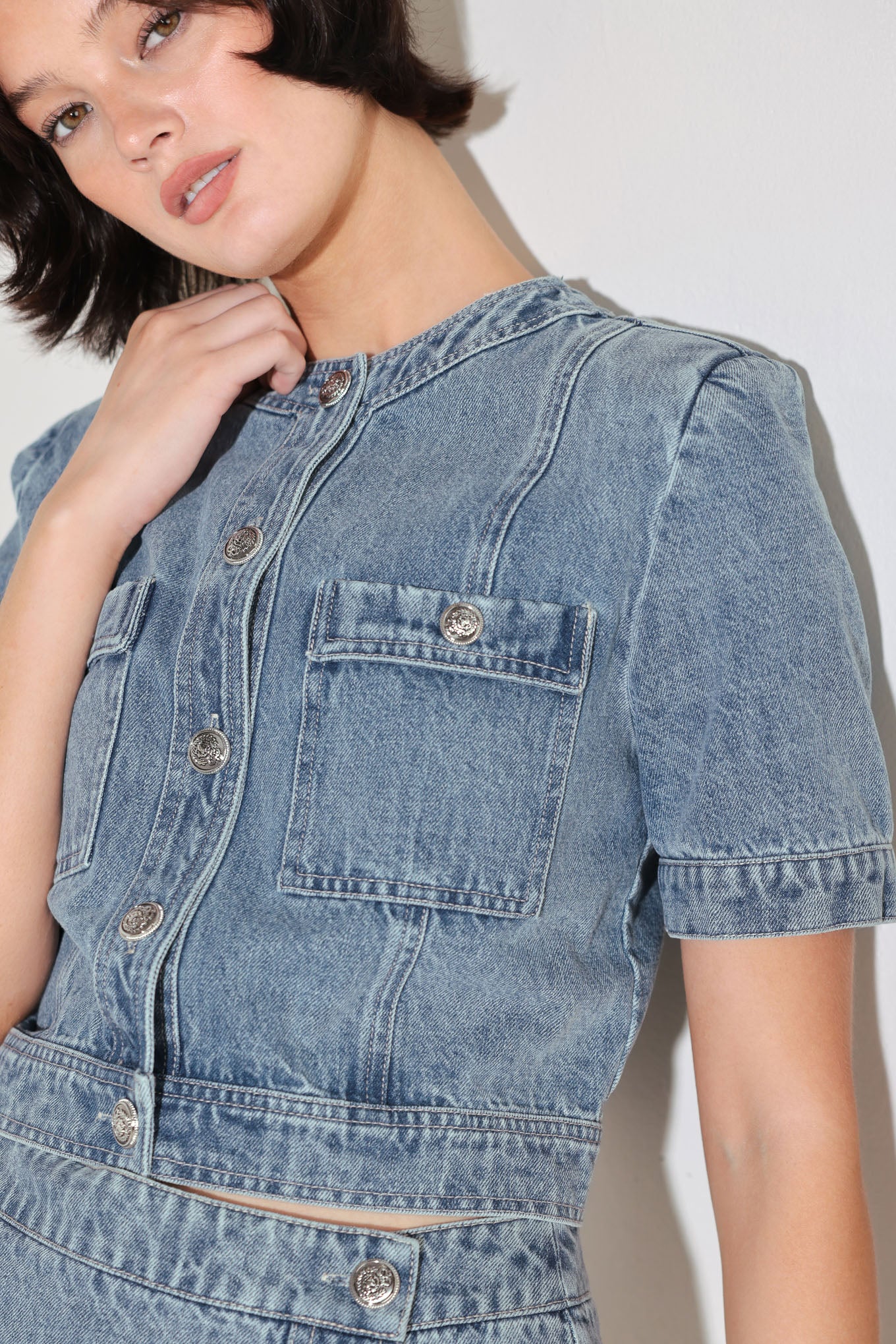 A washed denim jacket featuring round neckline, short sleeve, front pockets and front button down. Matching skort FP2018T
Details:
Self : 100% Cotton
Size & Fit
- Model is 5`8" And Wearing Size Small
- Measurements Taken From Size Small
- Approx. Length: 19"