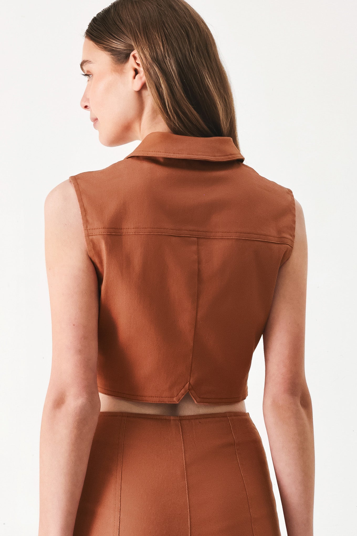 Woman wearing a brown sleeveless crop top with collar, sleeveless, pockets and front button down | FREEMARKET | Flying Tomato