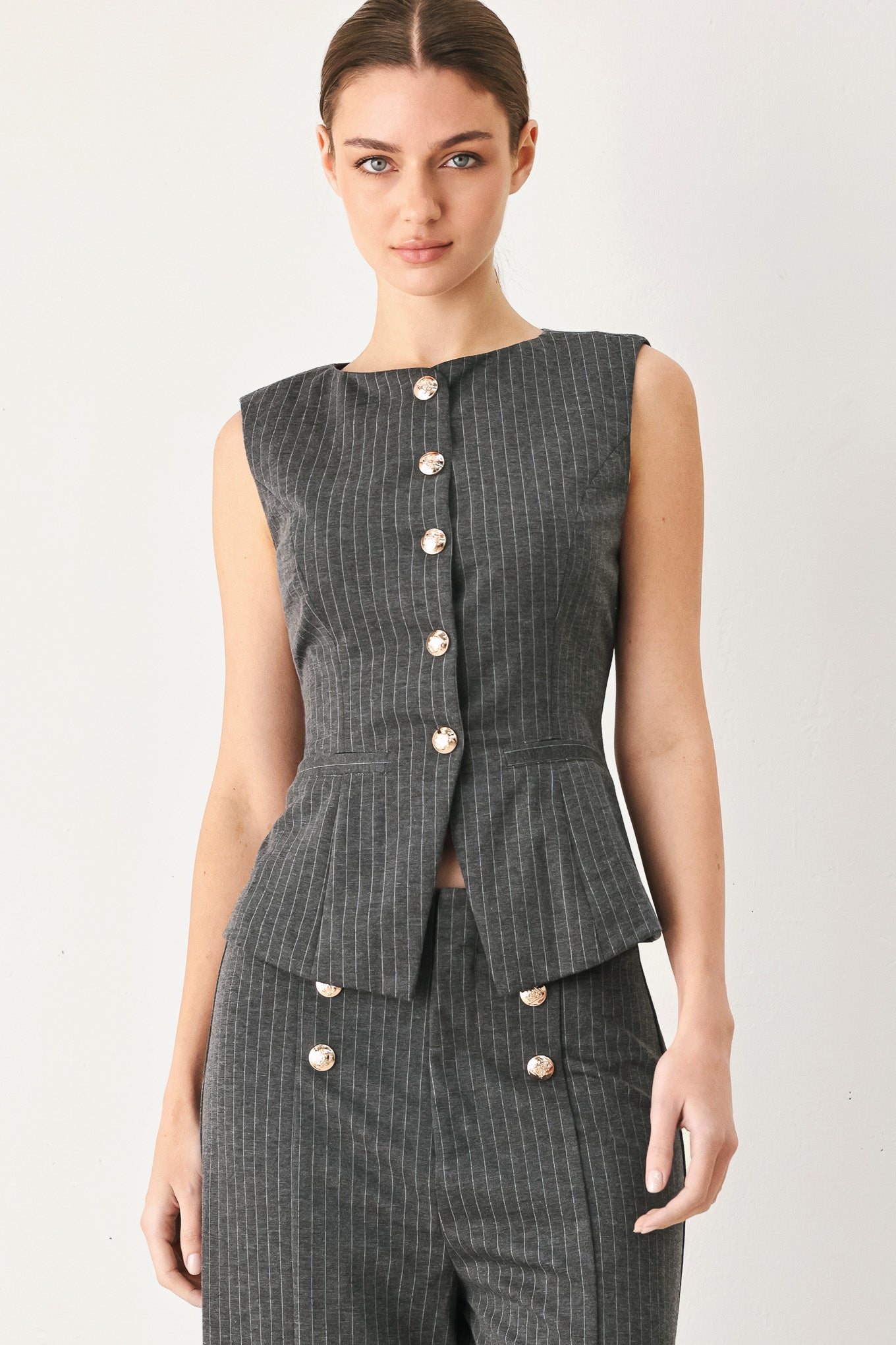 Woman wearing a charcoal and white striped stretch woven vest with wide neckline, sleeveless and front button closure | FREEMARKET