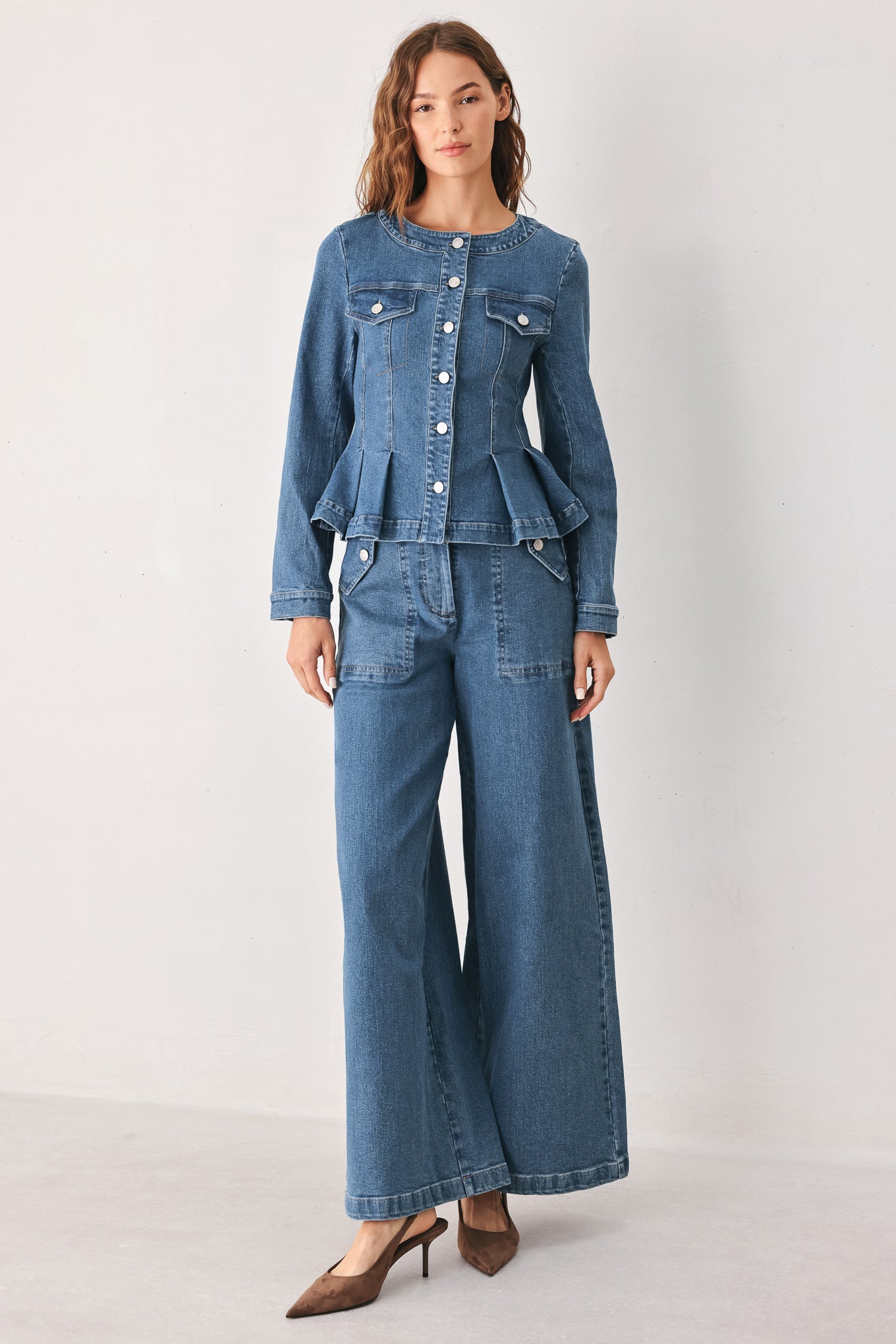 A woman wearing a cropped blue denim jacket with silver buttons and peplum waist | FREEMARKET