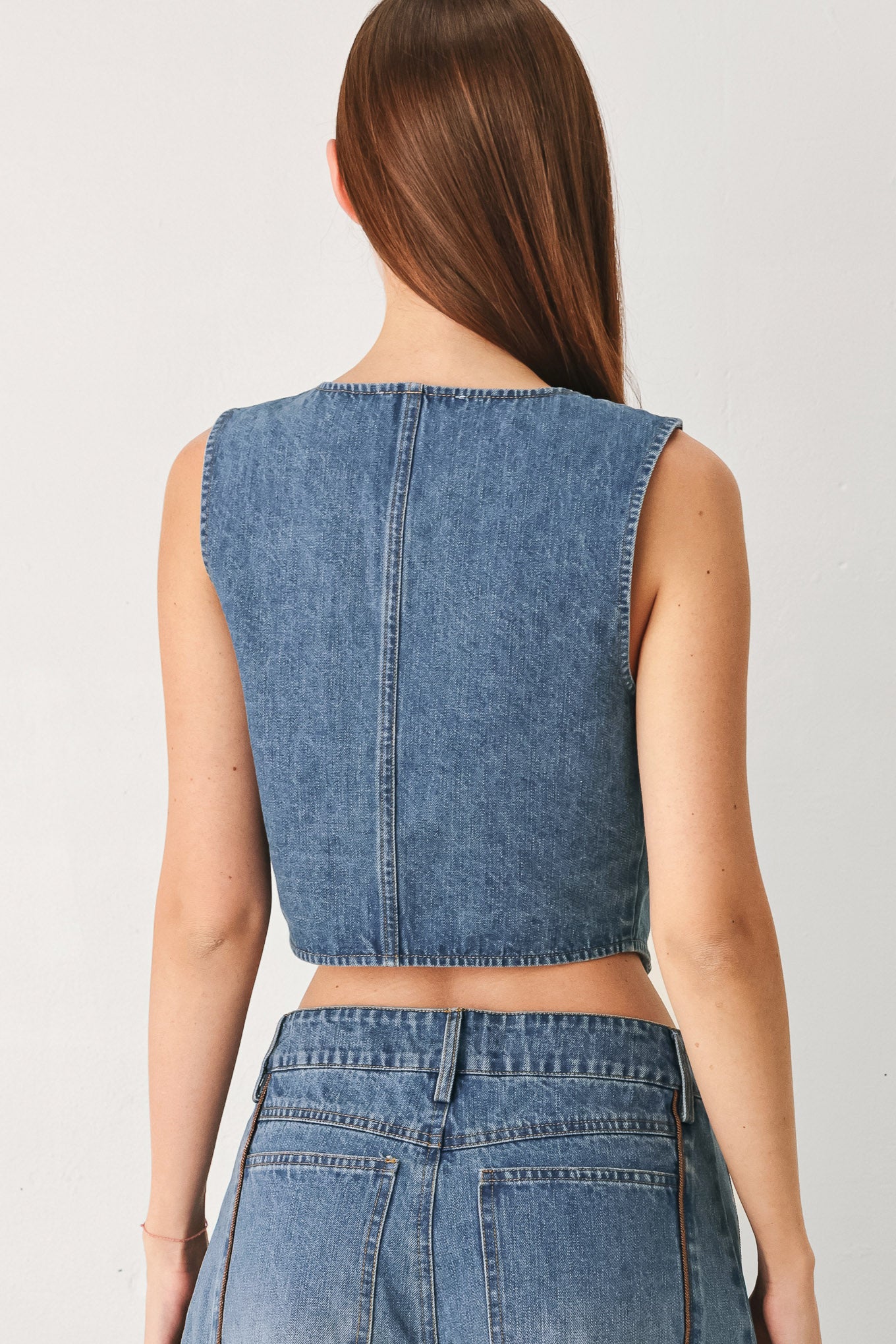 Woman wearing a denim vest with front button down and piping detail | FREEMARKET