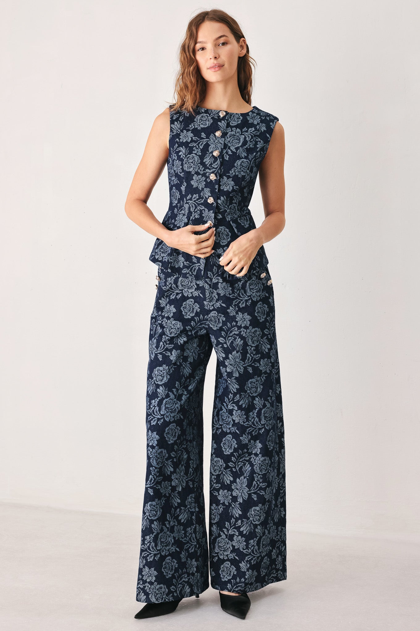 A woman wearing a sleeveless navy blue denim jacquard vest with a light blue floral pattern and gold-tone buttons down the front | FREEMARKET