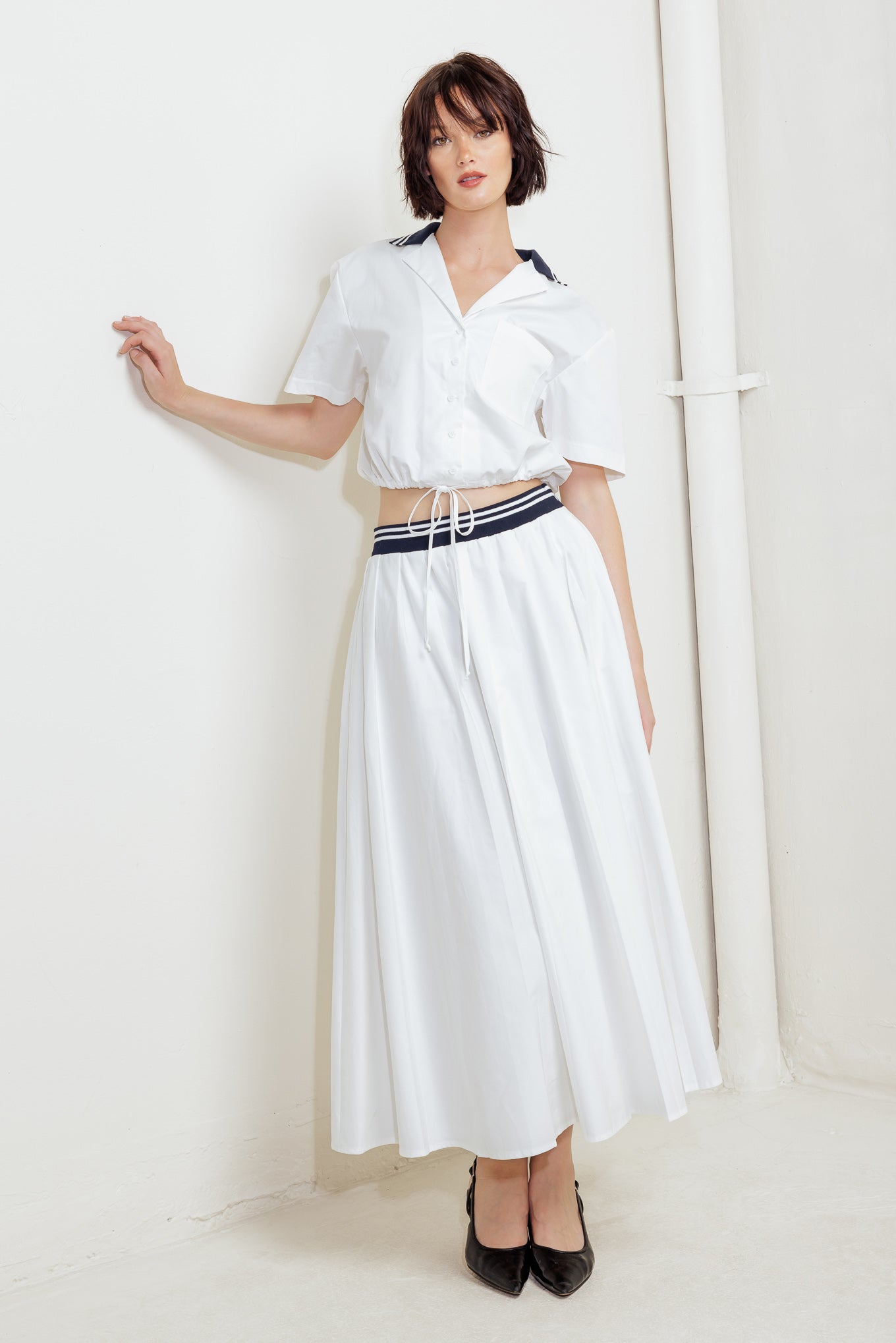 A solid woven midi skirt with contrasting waistband and side zipper closure.