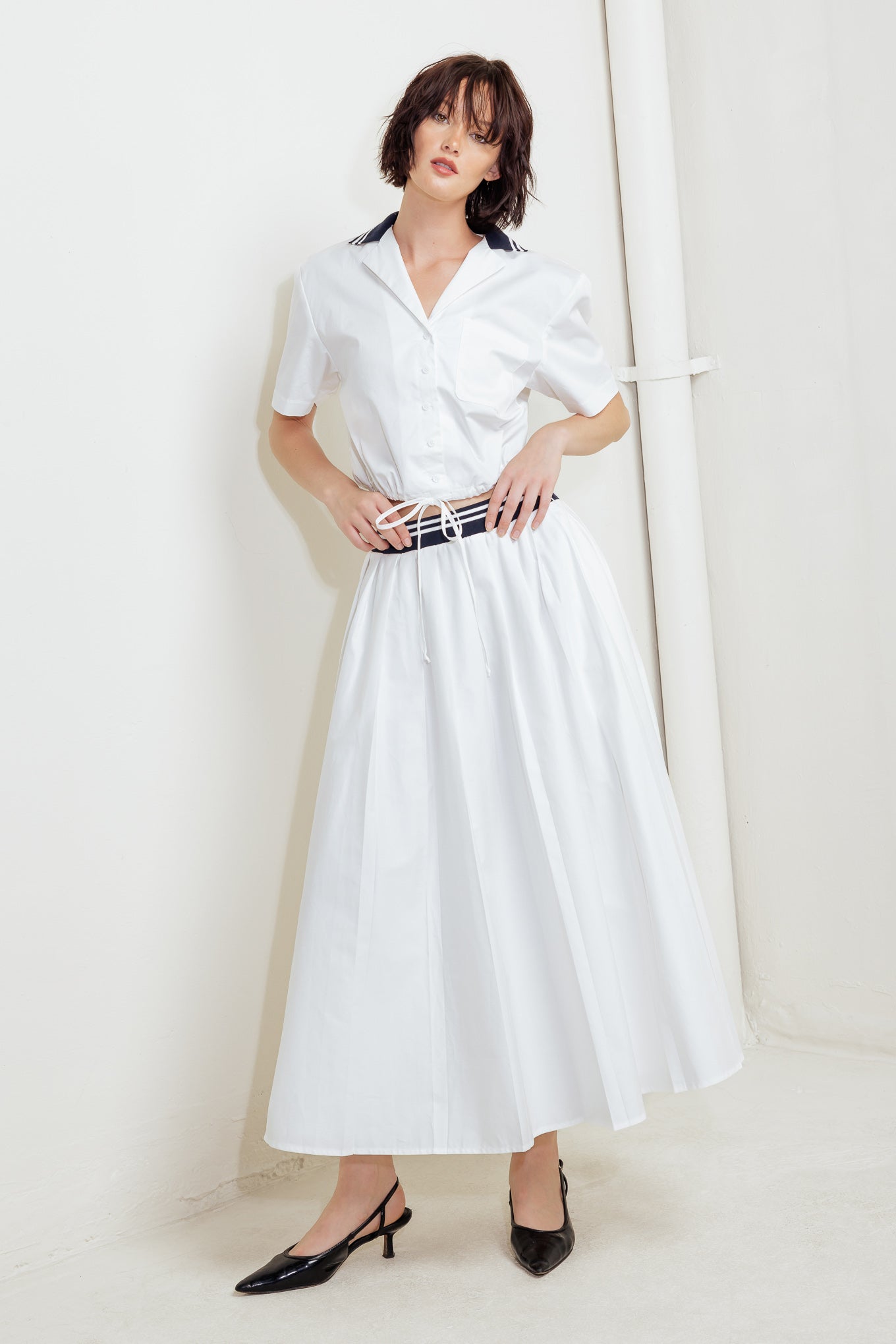 A solid woven midi skirt with contrasting waistband and side zipper closure.