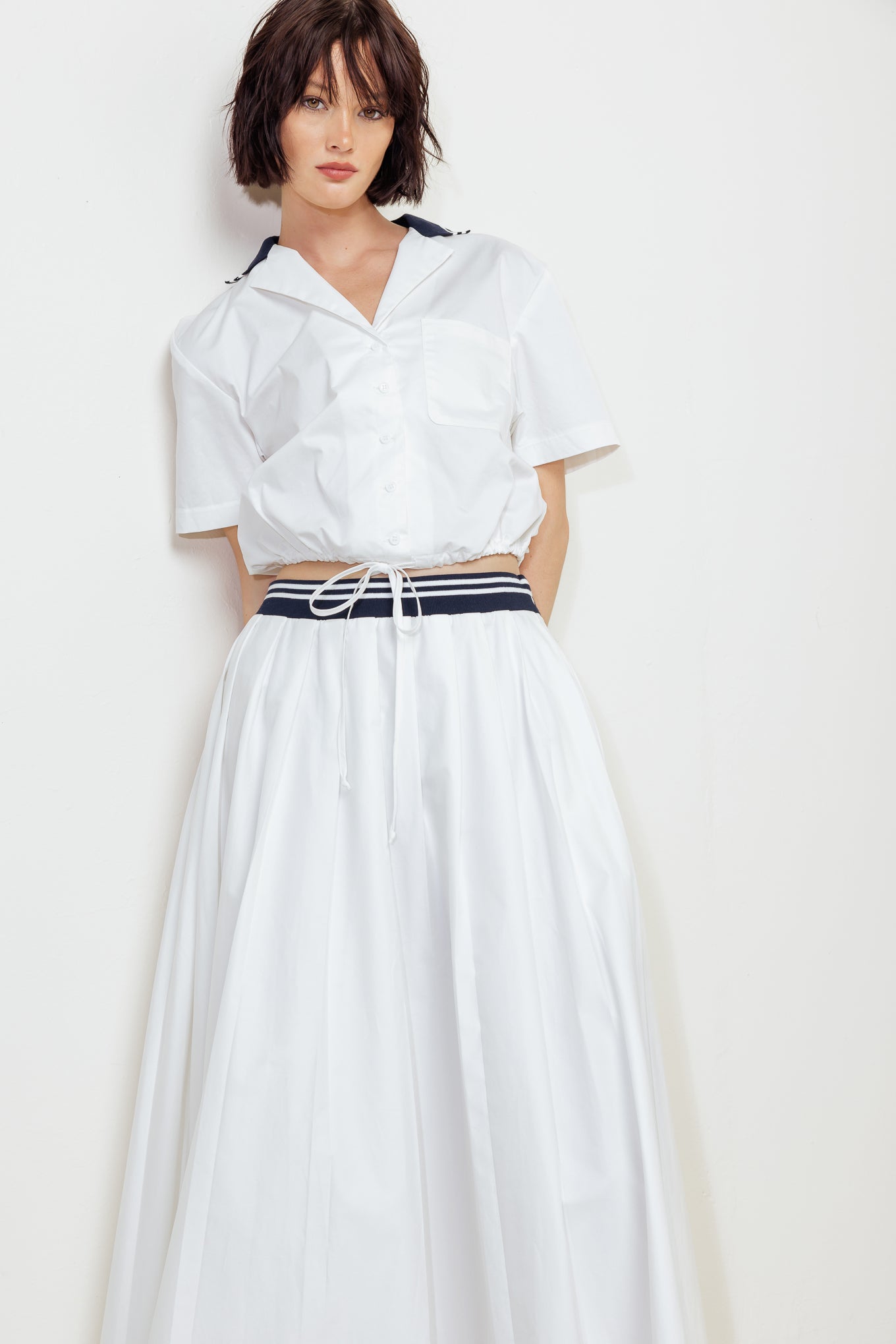 A solid woven midi skirt with contrasting waistband and side zipper closure.