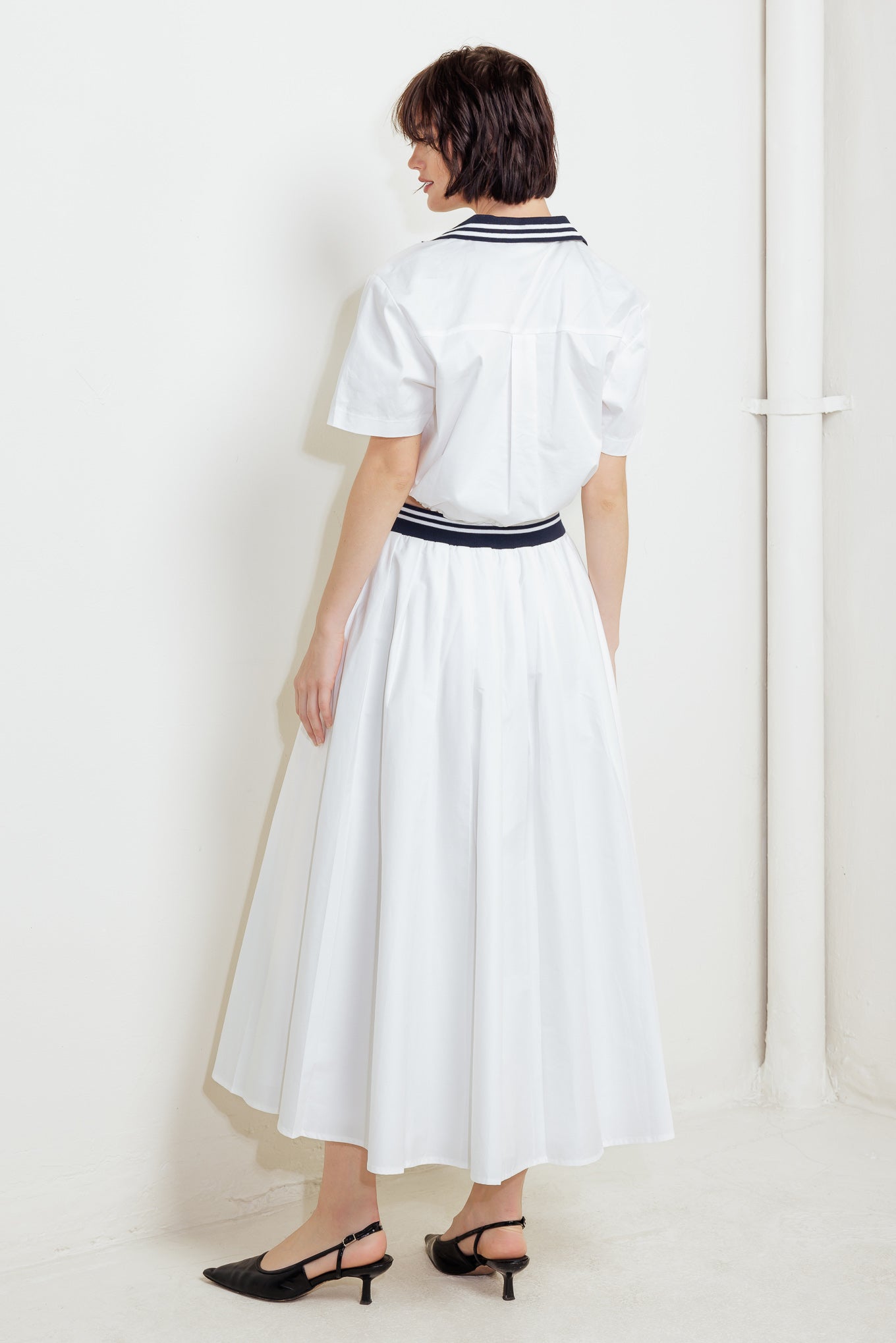 A solid woven midi skirt with contrasting waistband and side zipper closure.