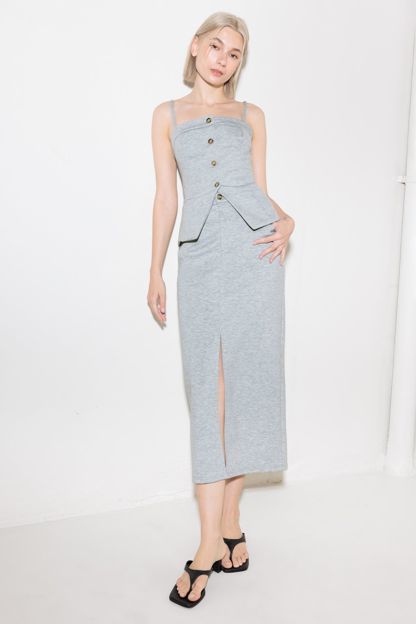 A solid knit skirt featuring pencil skirt, front closure, back pocket and front slit.