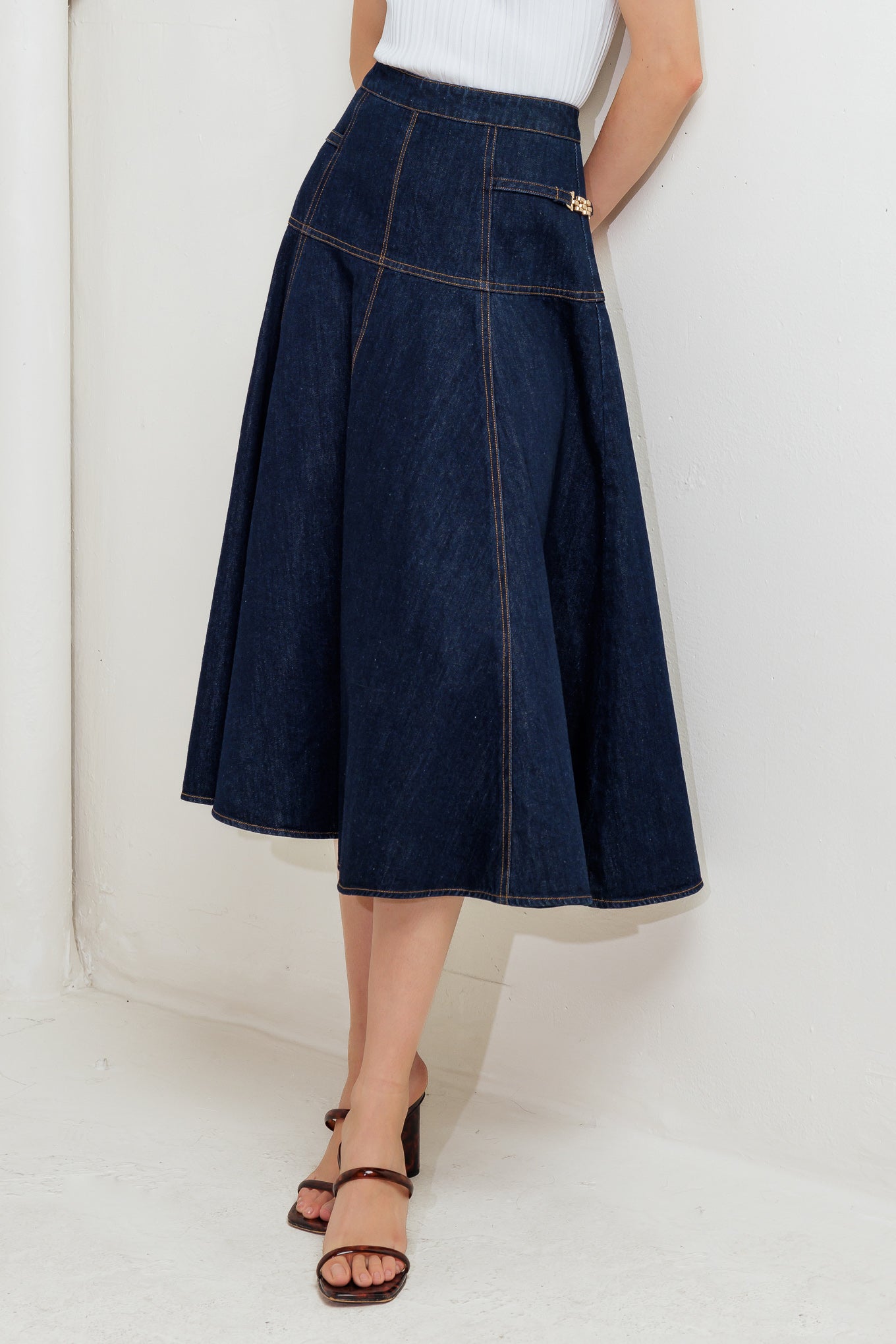 A denim skirt featuring side hardware trim, circle skirt and back zipper closure.