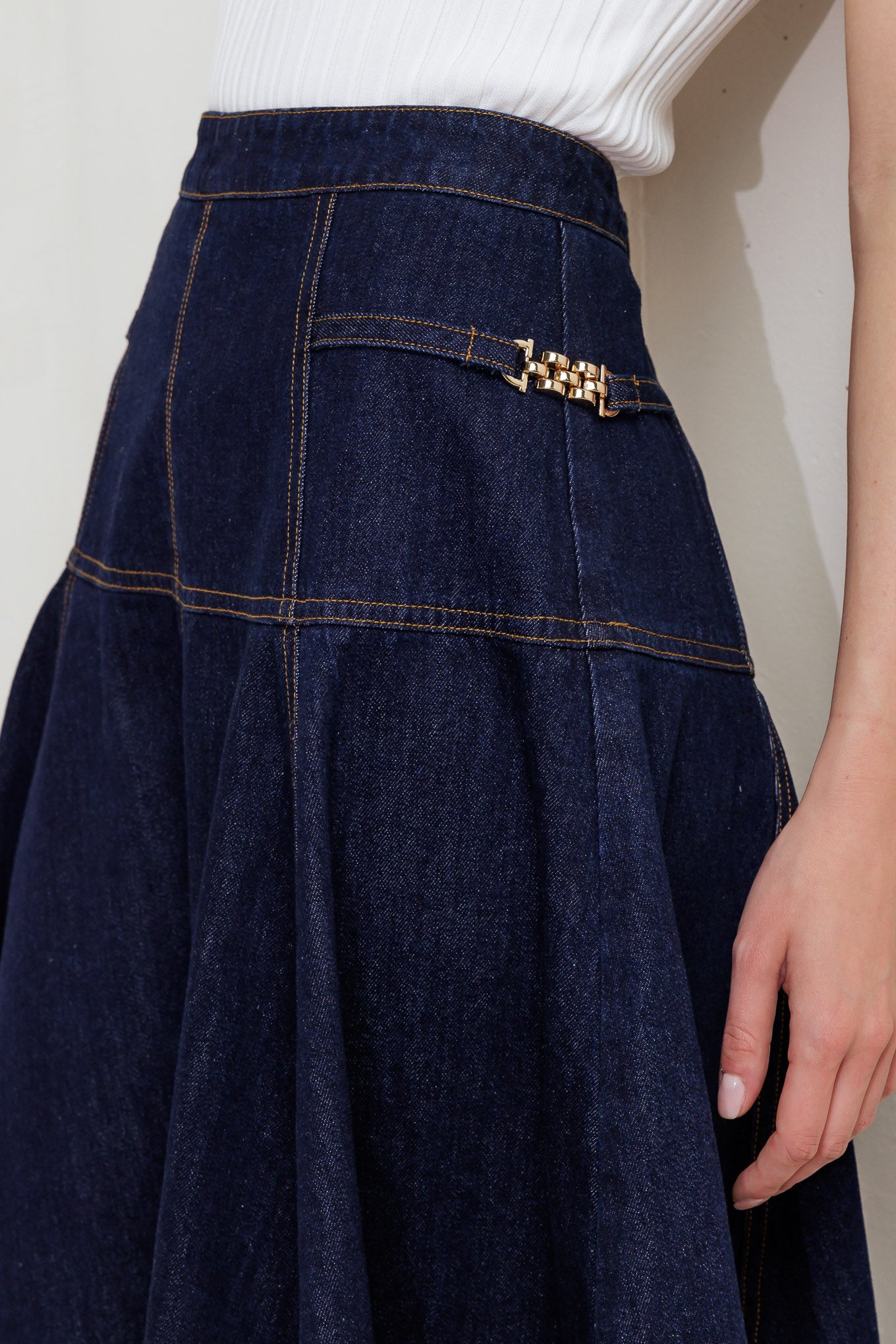 A denim skirt featuring side hardware trim, circle skirt and back zipper closure.