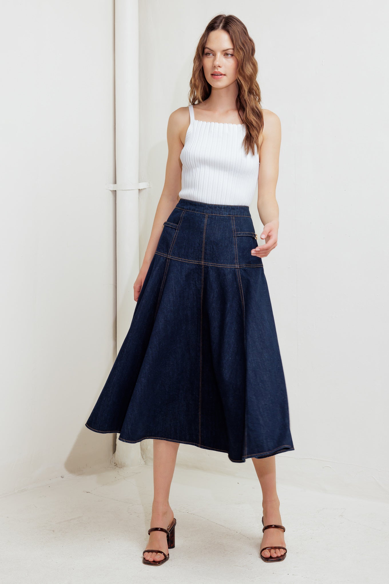 A denim skirt featuring side hardware trim, circle skirt and back zipper closure.