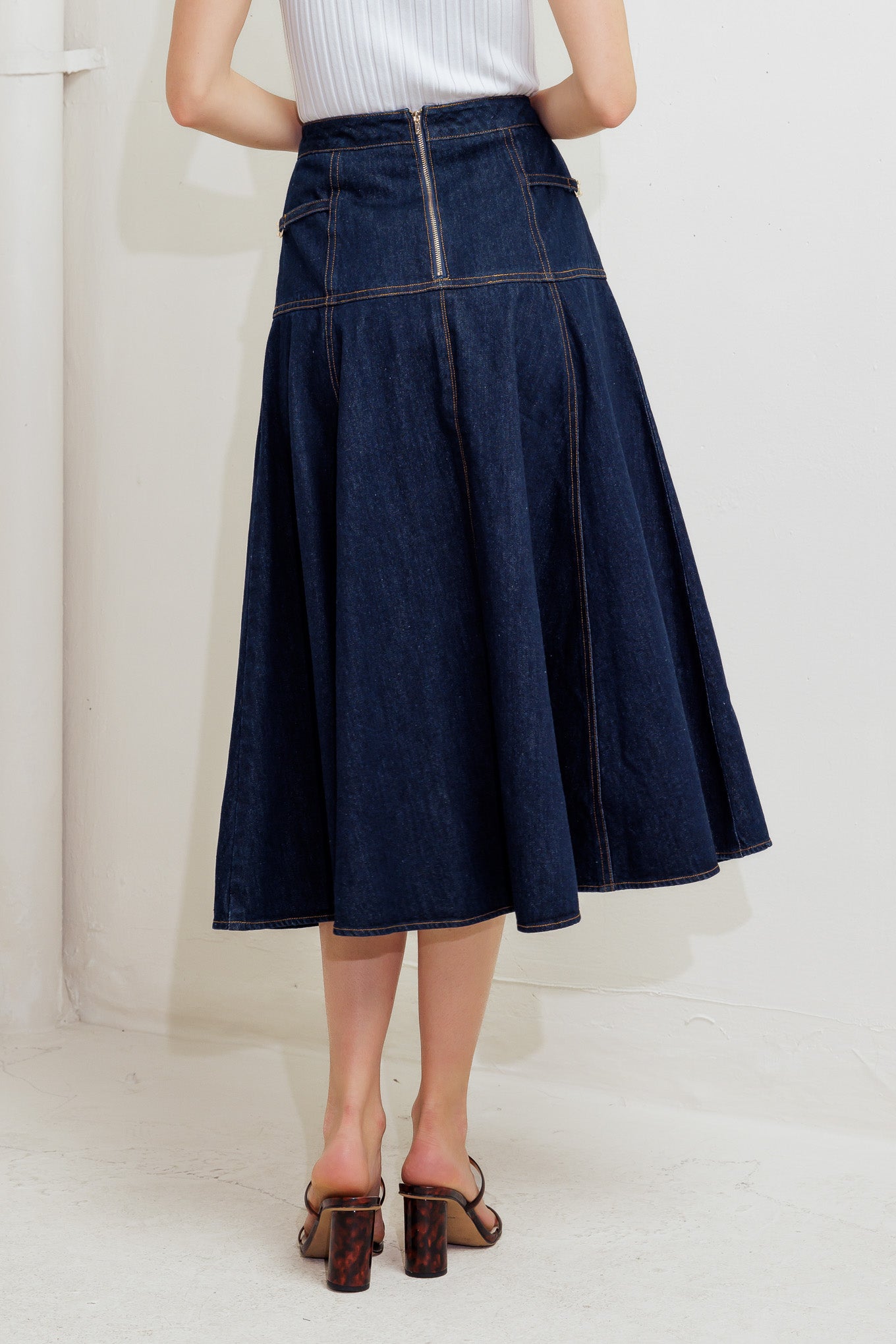 A denim skirt featuring side hardware trim, circle skirt and back zipper closure.