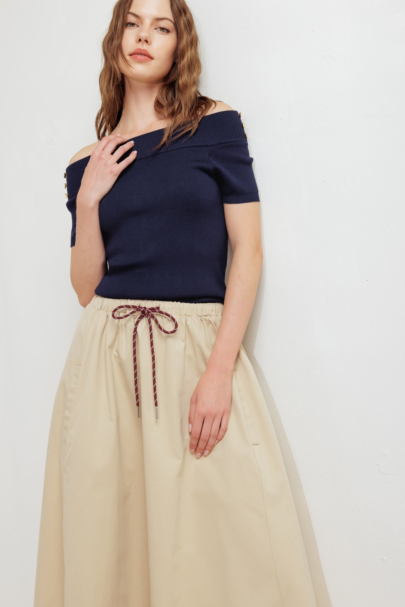 A solid woven midi skirt featuring elasticized waistband with contrasting front tie, side pockets and full skirt