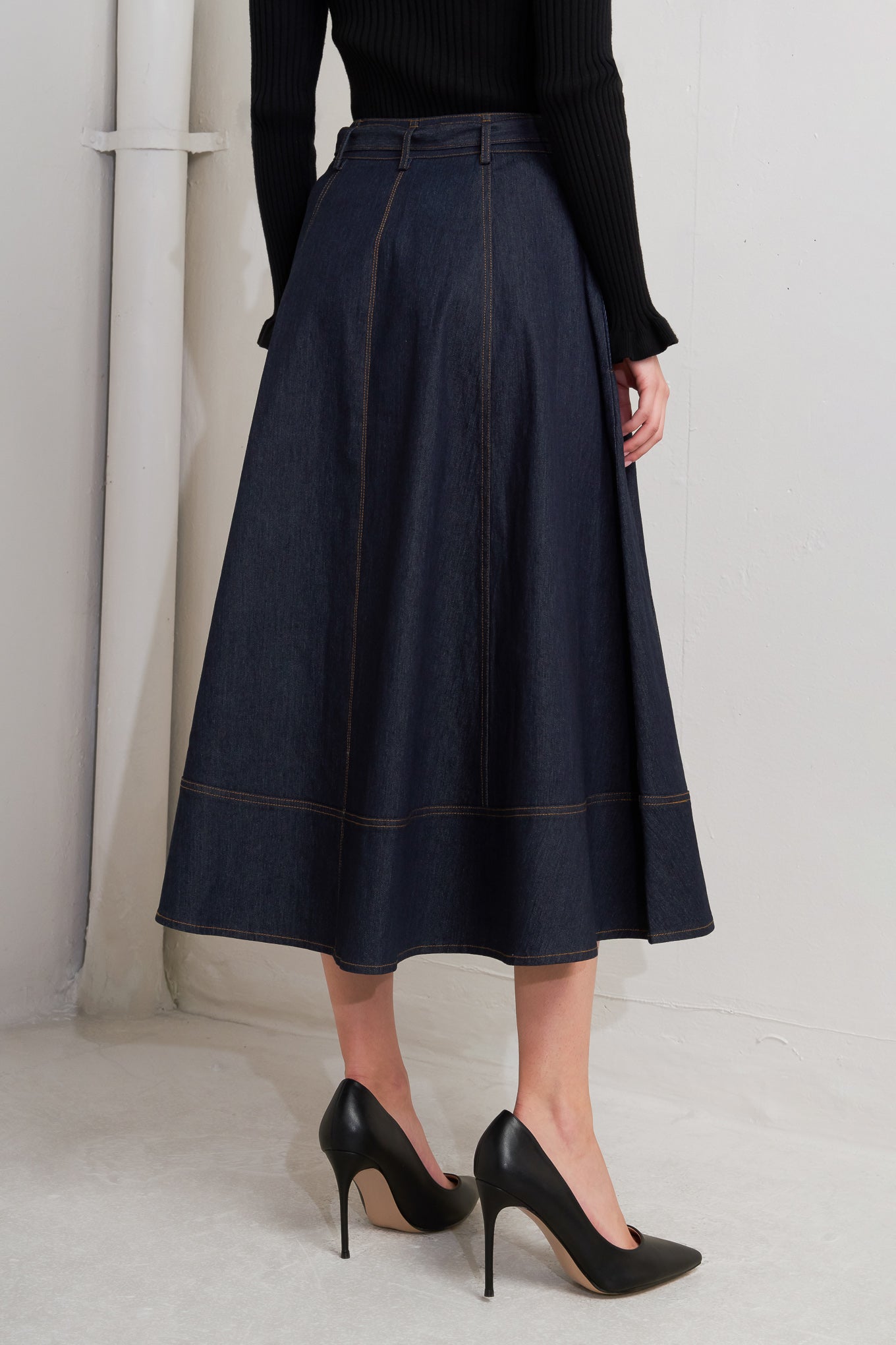 A denim circle skirt featuring self belt, front button down and wide hemline