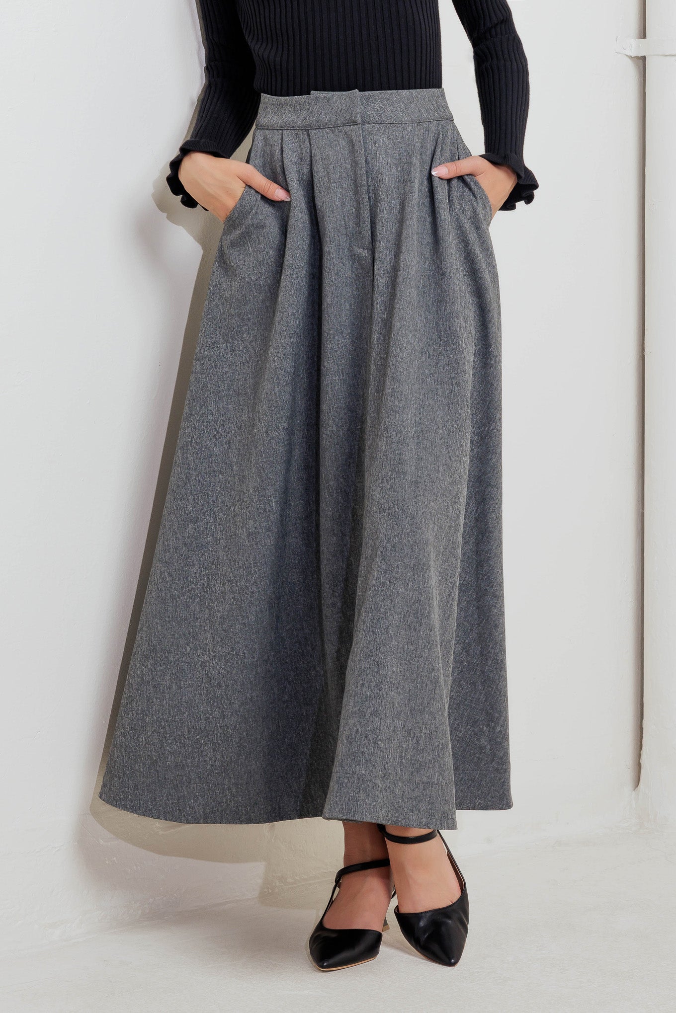 A solid woven midi circle skirt featuring front closure and side pockets.