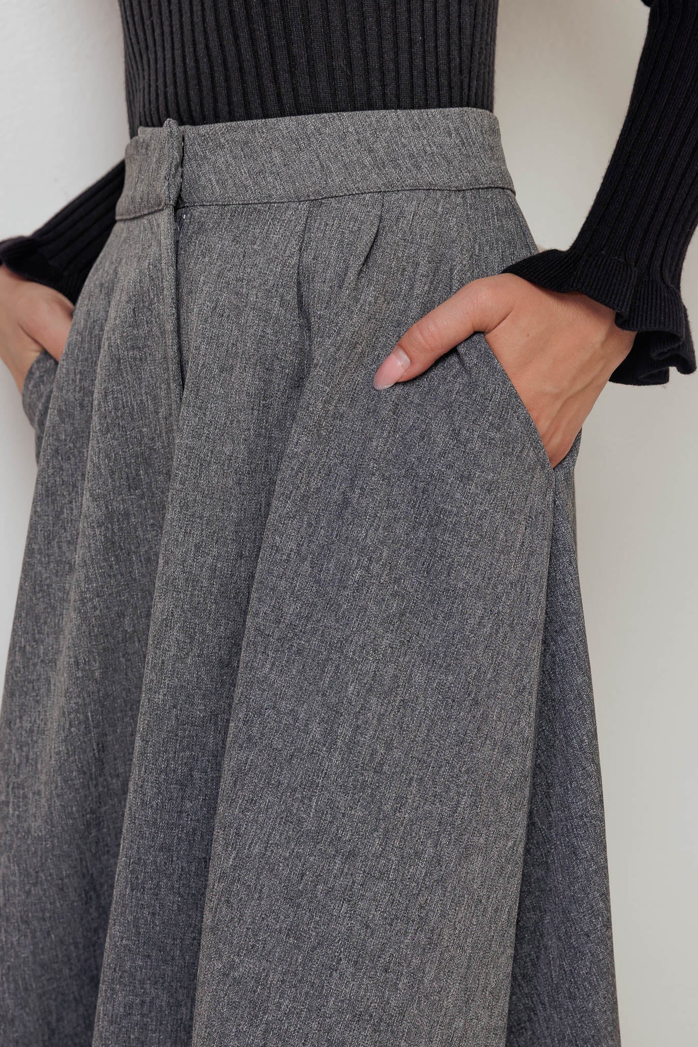 A solid woven midi circle skirt featuring front closure and side pockets.