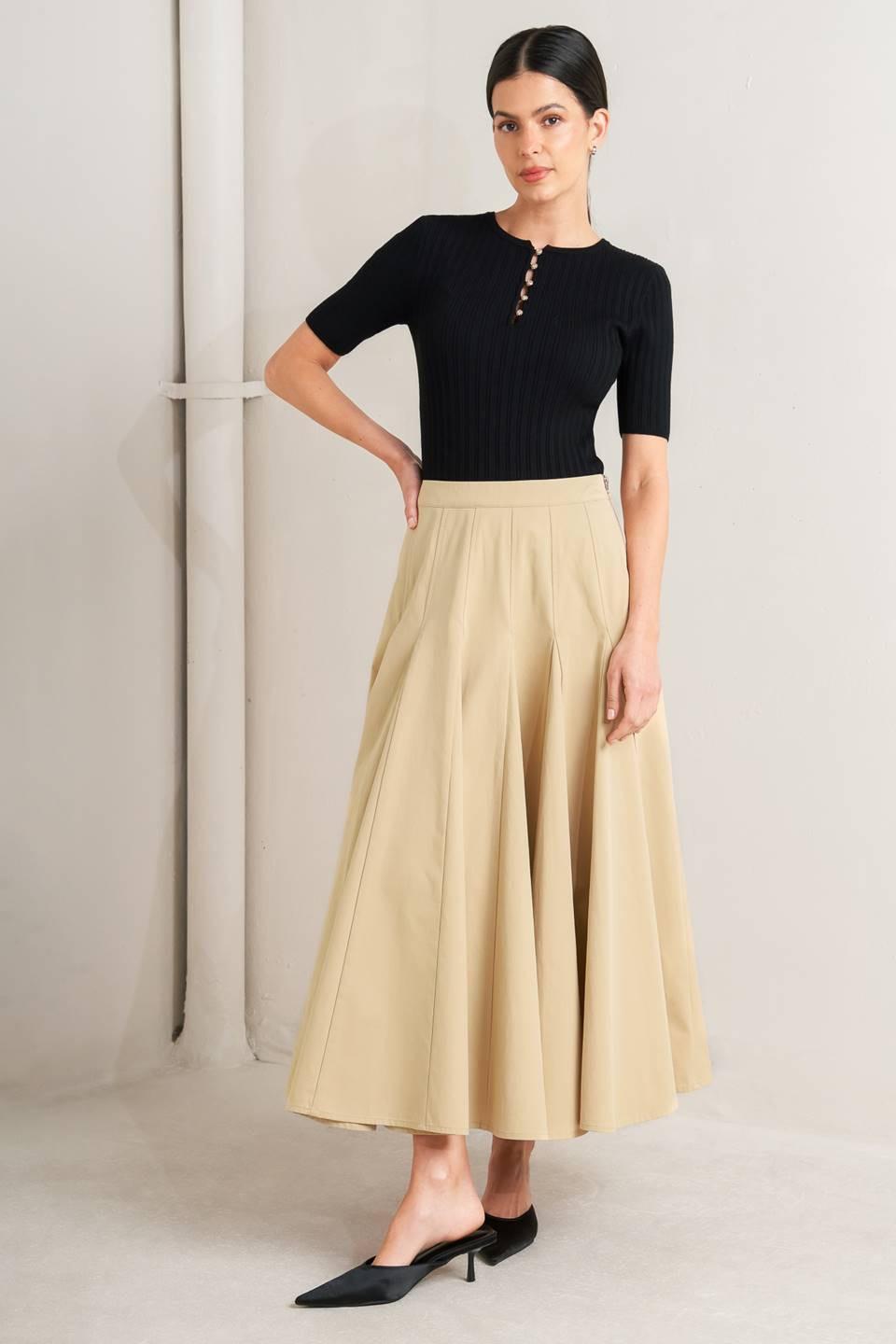 Woman wearing a black top and beige skirt against a neutral background - FLYING TOMATO