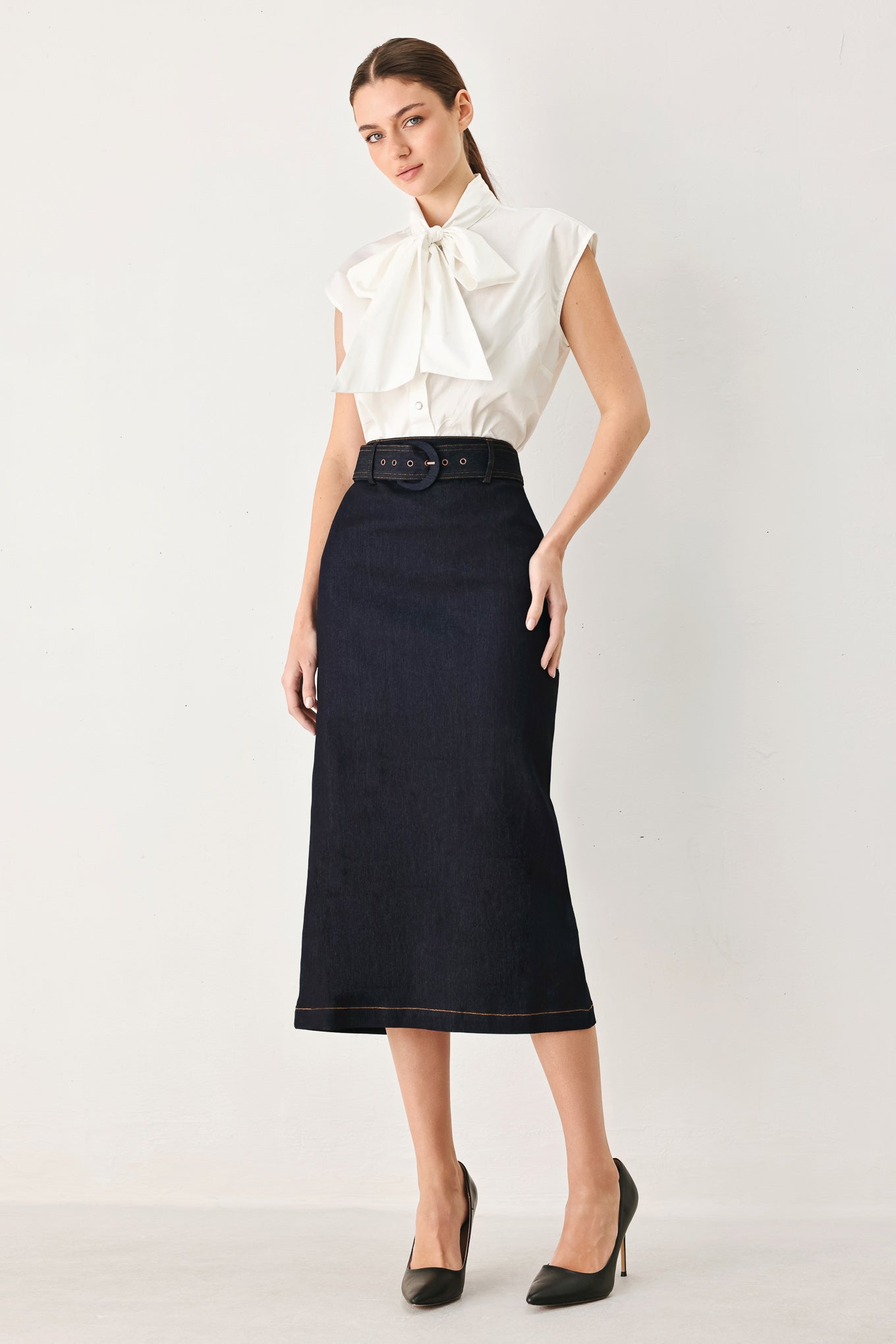Woman wearing a dark blue denim mini pencil skirt with self belt, back slit and zipper closure | FREEMARKET