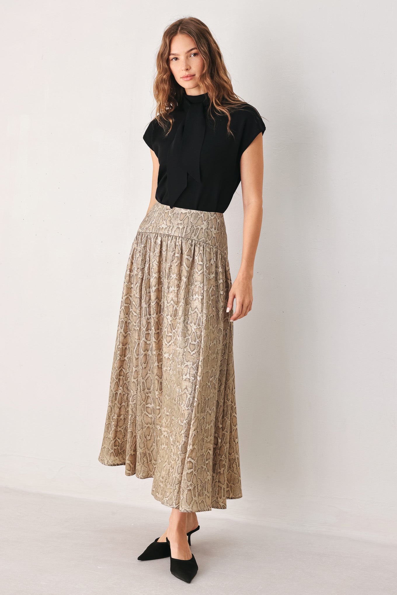 A woman wearing a high-waisted, A-line midi skirt with an all-over beige and brown snakeskin pattern | FREEMARKET
