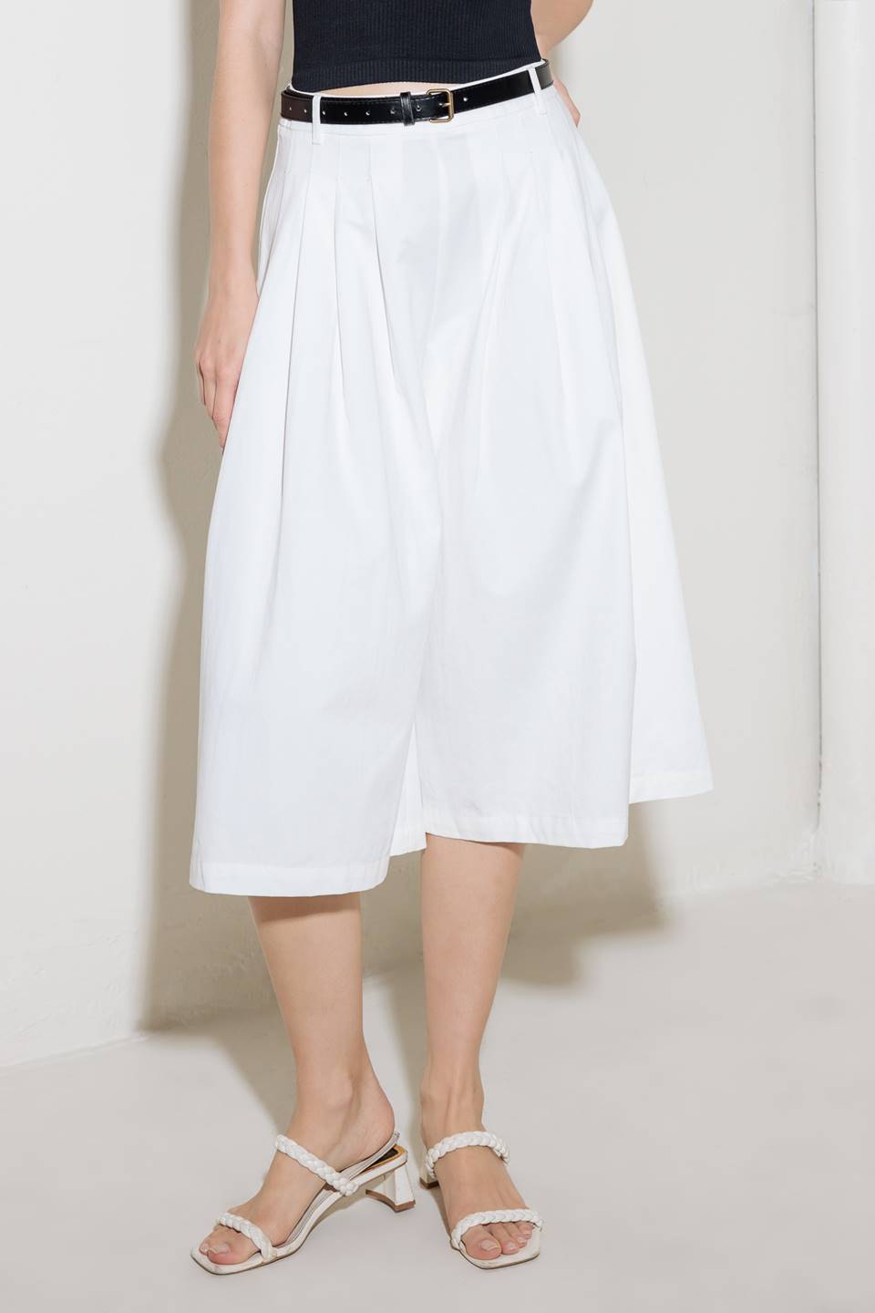 A solid woven culotte pant with front pleat, belt and side zipper closure.