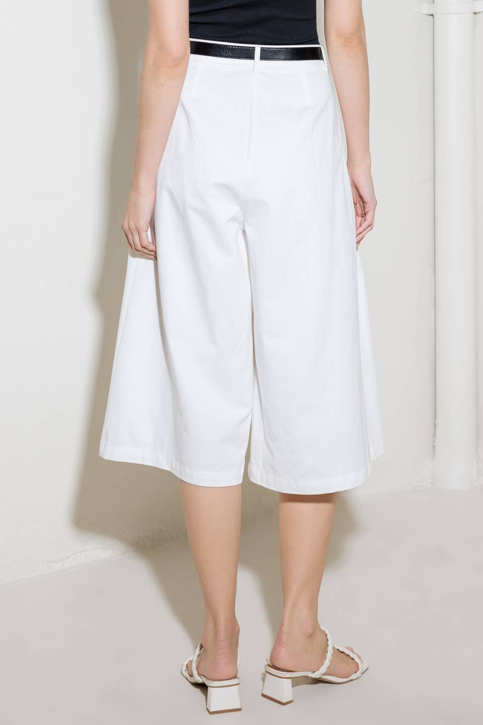 A solid woven culotte pant with front pleat, belt and side zipper closure.