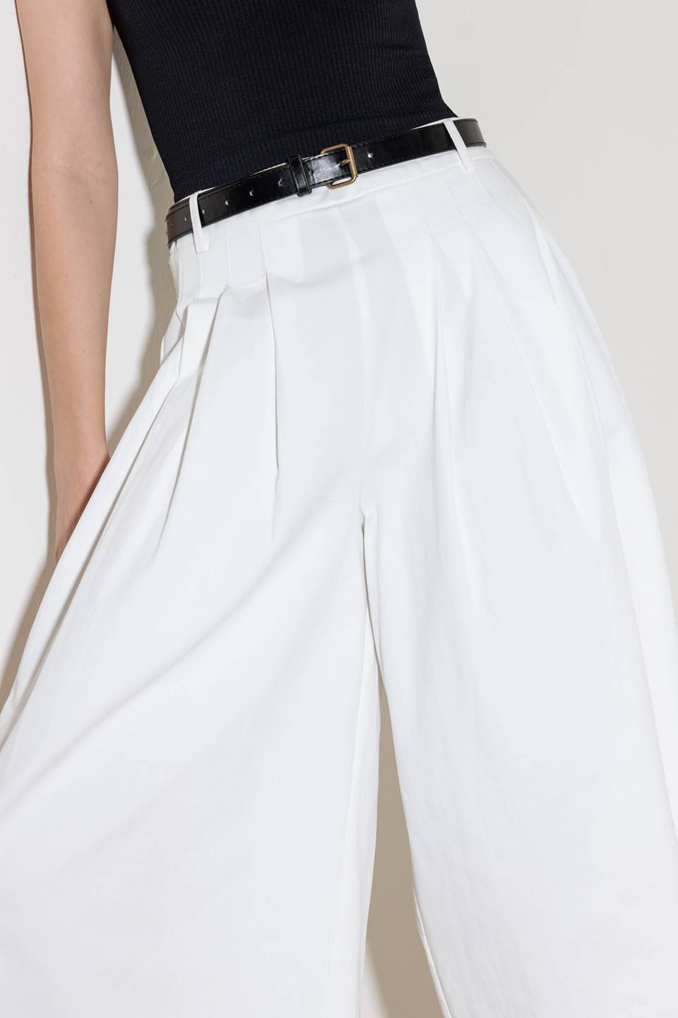 A solid woven culotte pant with front pleat, belt and side zipper closure.