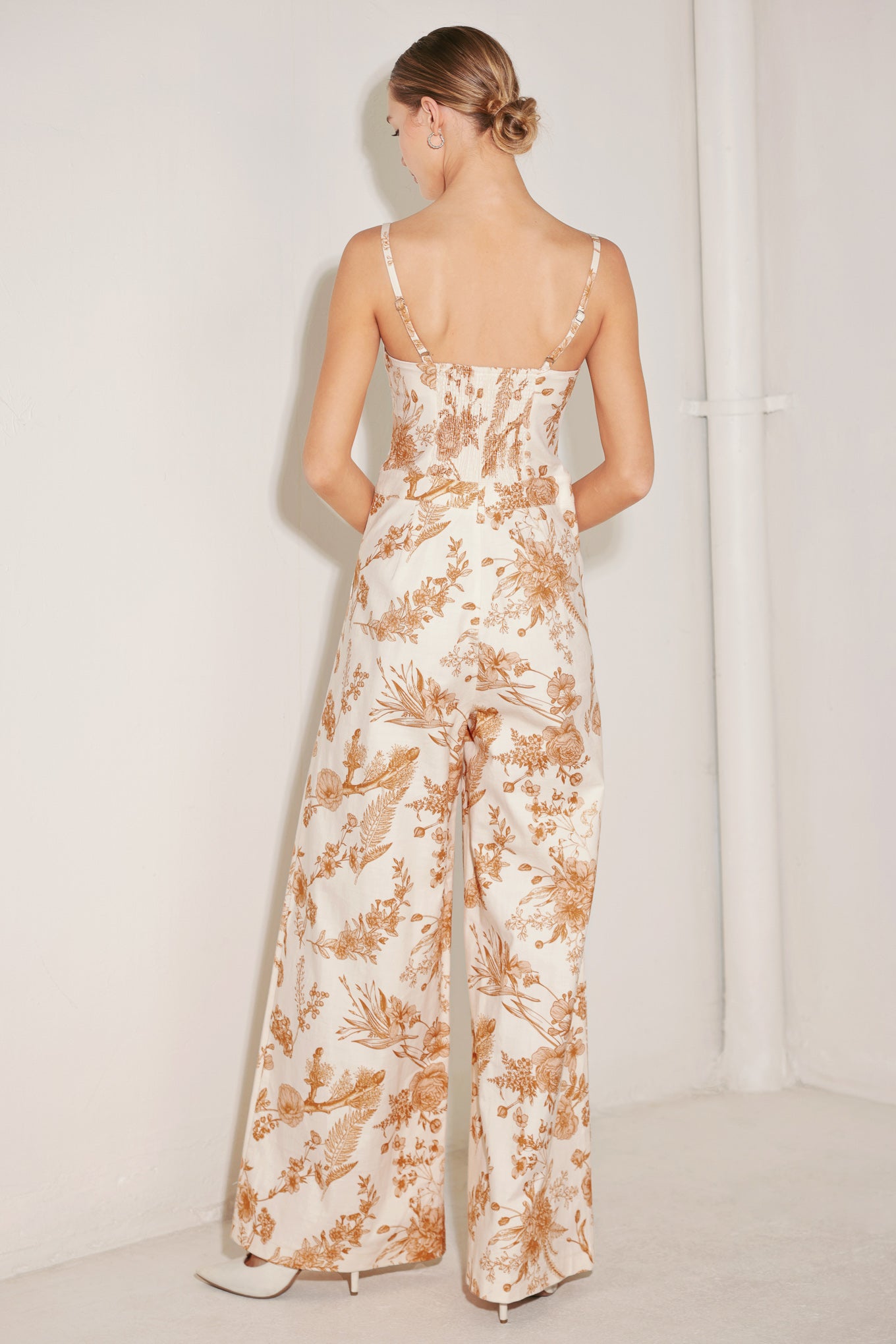 A printed woven jumpsuit featuring straight neckline, straps, front button, zipper closure, side pocket, wide leg and smocked back bodice
Details:
Self : 97% Cotton 3% Spandex
Size & Fit
- Model is 5`8" And Wearing Size Small
- Measurements Taken From Size Small
- Approx. Length: 59"