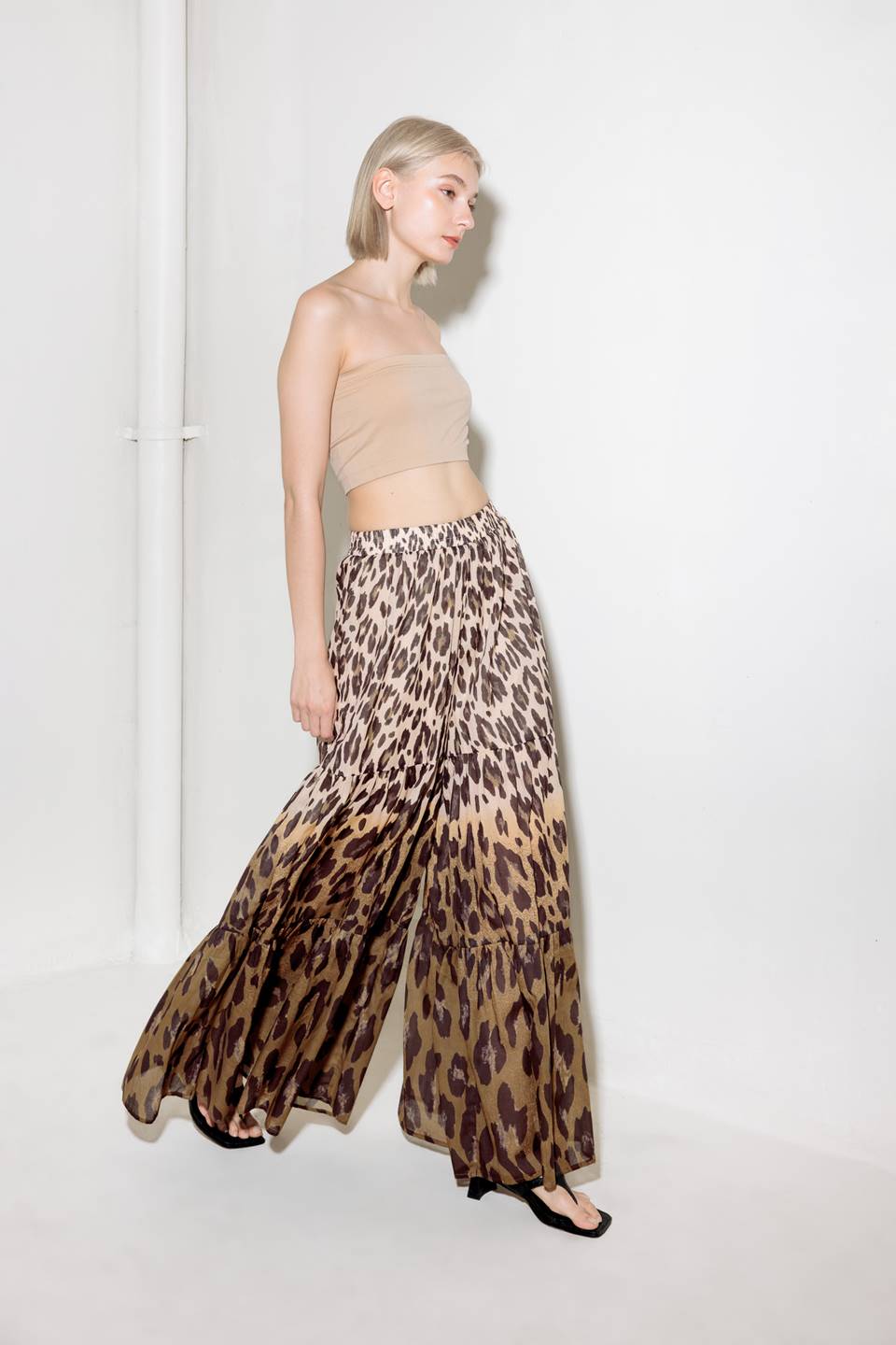 A printed woven pant featuring smocked waistband and tiered bottom with wide leg.