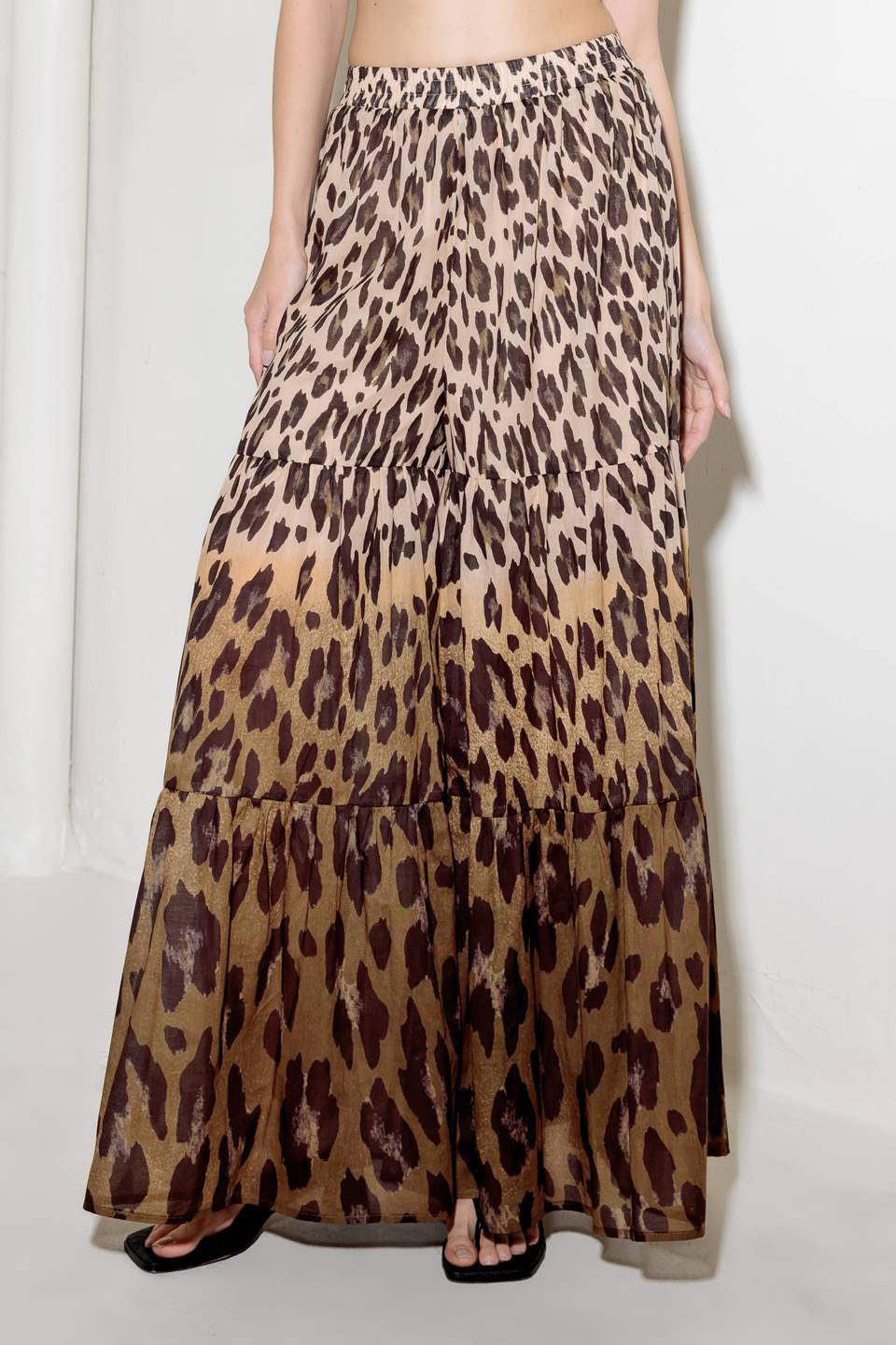 A printed woven pant featuring smocked waistband and tiered bottom with wide leg.