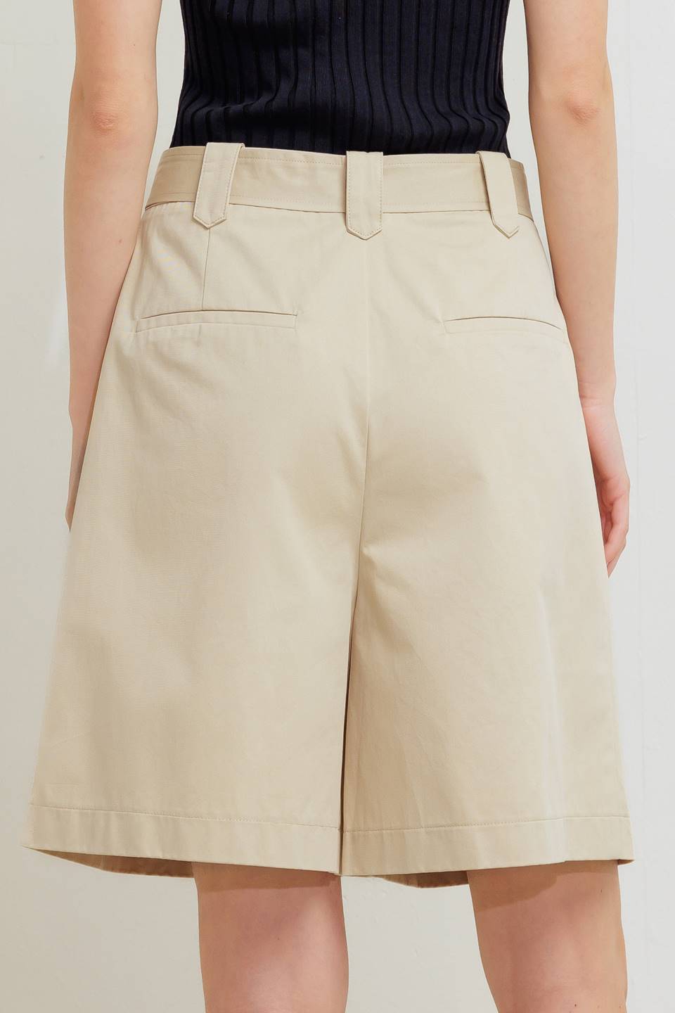 A solid woven bermuda short featuring front closure and self belt.