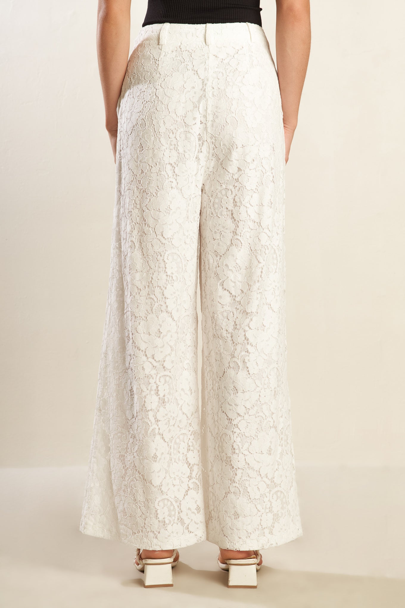 A white woven lace pant featuring side pockets, belt loops, front closure and wide leg.