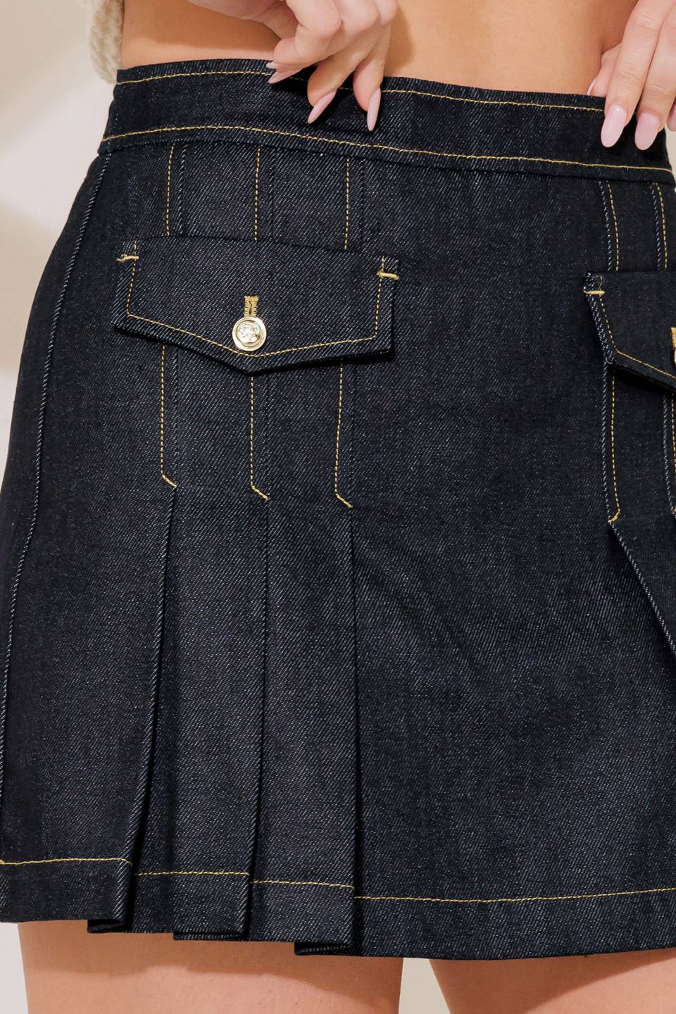 A rigid denim skort featuring front pocket, pleated front and back zipper closure