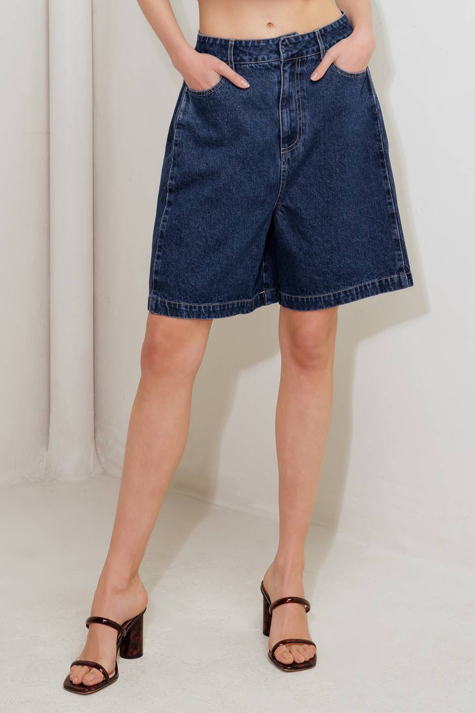 A washed denim short featuring front closure and side/back pockets.