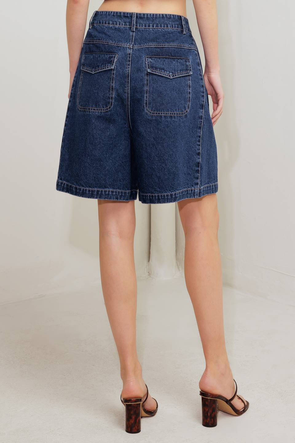 A washed denim short featuring front closure and side/back pockets.