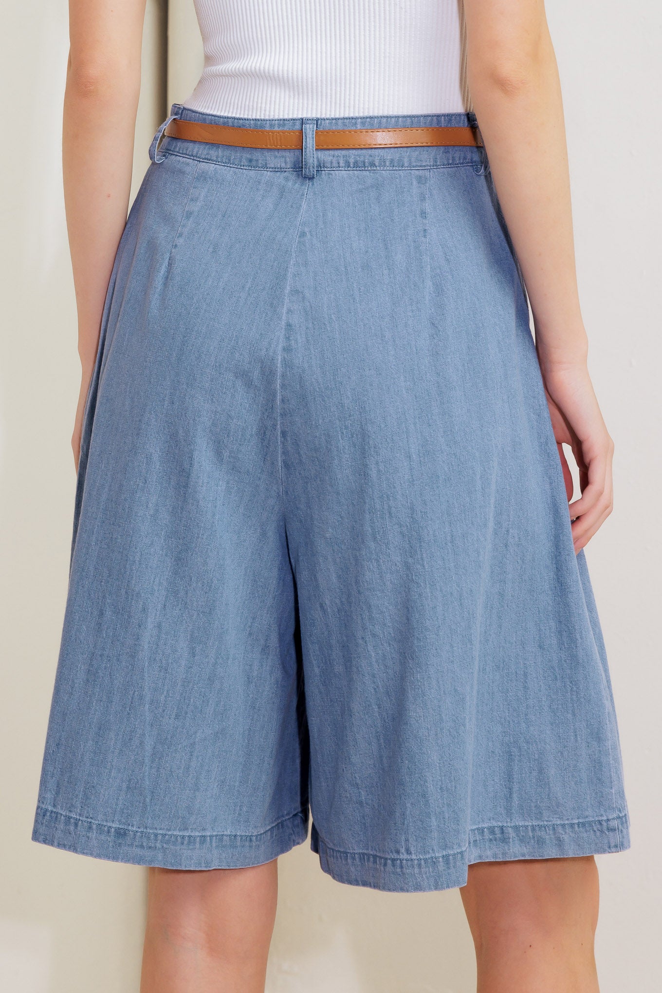 A washed chambray short featuring front pleats, belt, wide leg and side zipper closure.