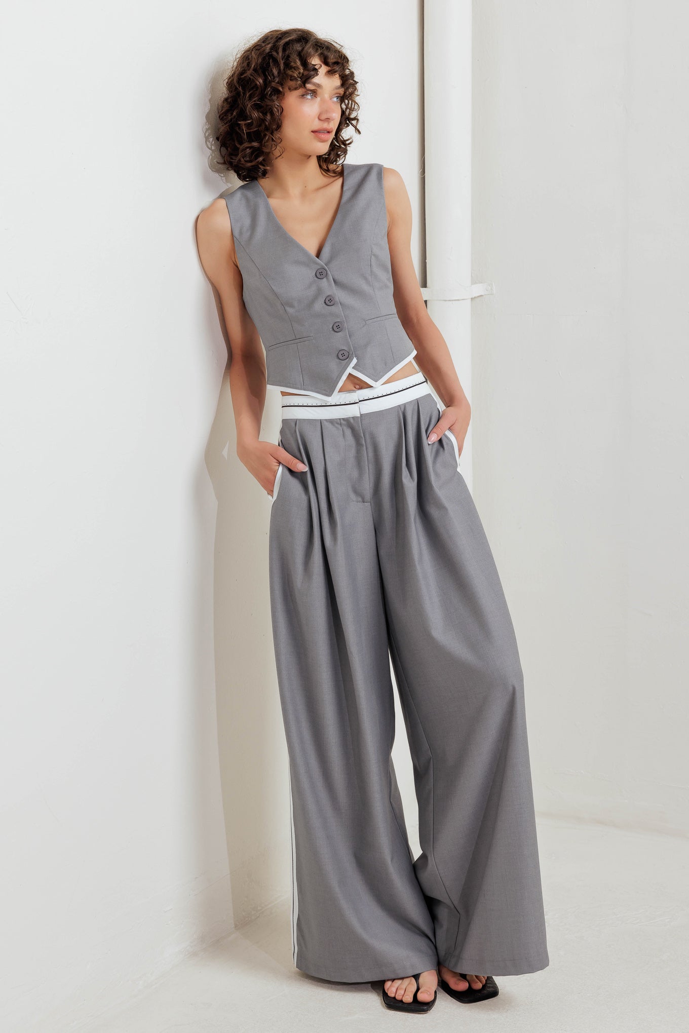 A solid woven pant featuring front closure, side pockets, contrasting waistband and side stripes and wide leg.