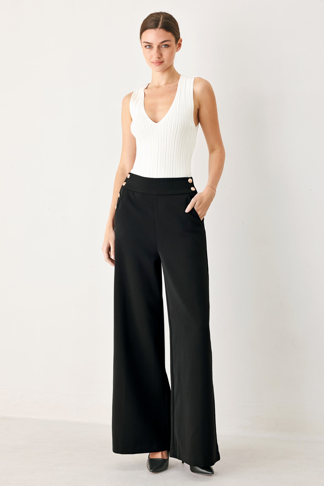 Woman wearing black wide-leg pants with gold button detail | FREEMARKET