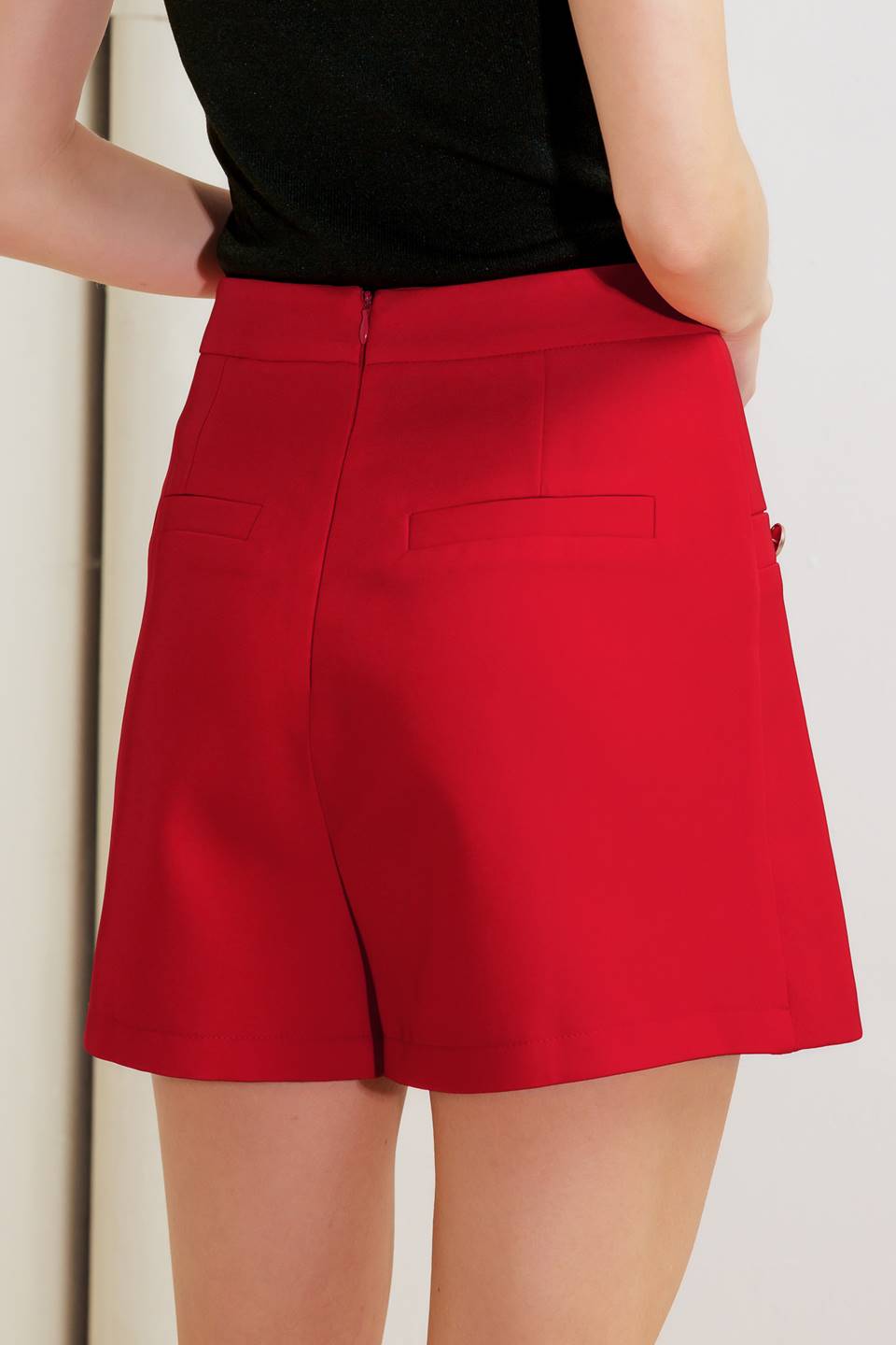 A solid red woven skort featuring side slit and back zipper closure