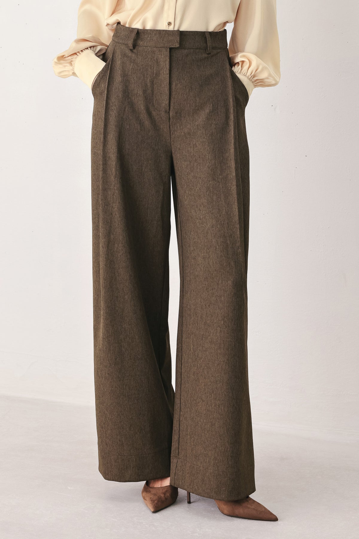 A woman wearing high-waisted, wide-leg brown trousers | FREEMARKET