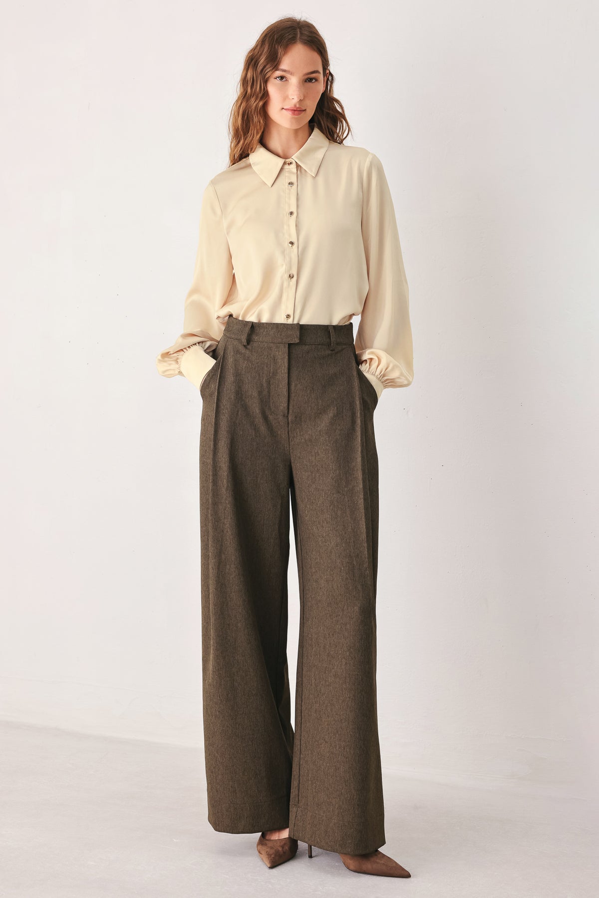 A woman wearing high-waisted, wide-leg brown trousers | FREEMARKET