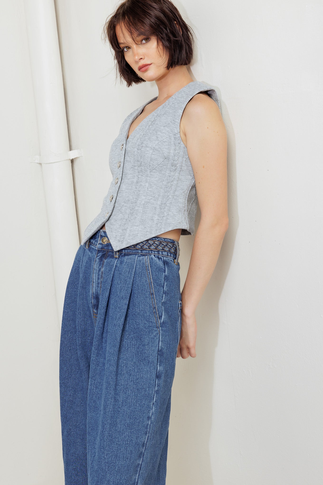A washed denim pant featuring braided waistband, front closure, side pockets and wide leg