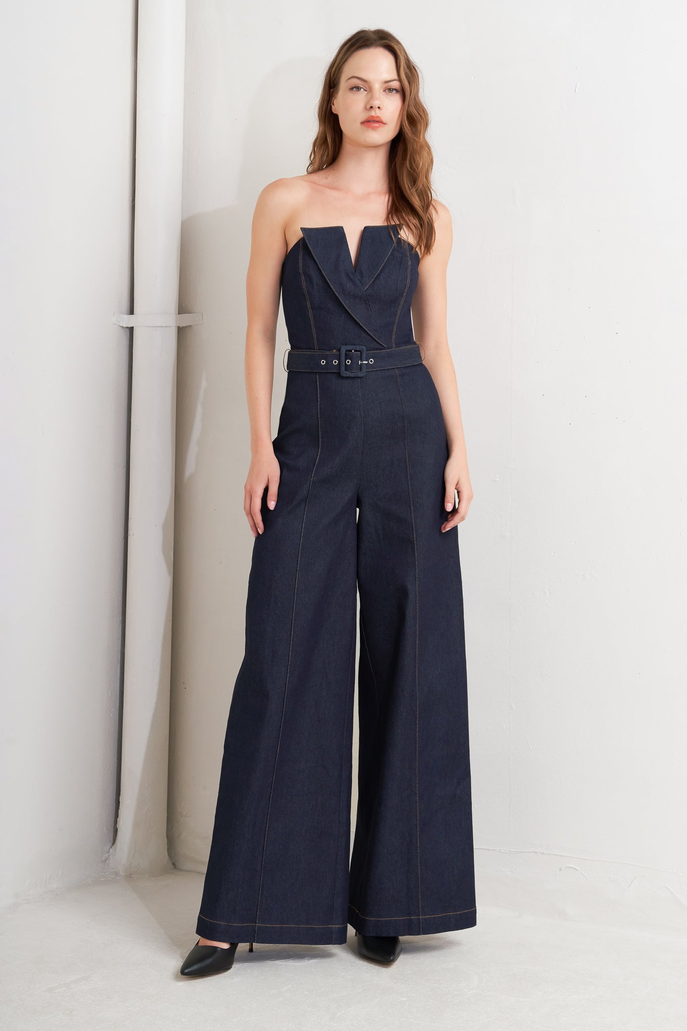 A denim jumpsuit featuring strapless, front fold over detail, self belt and wide leg