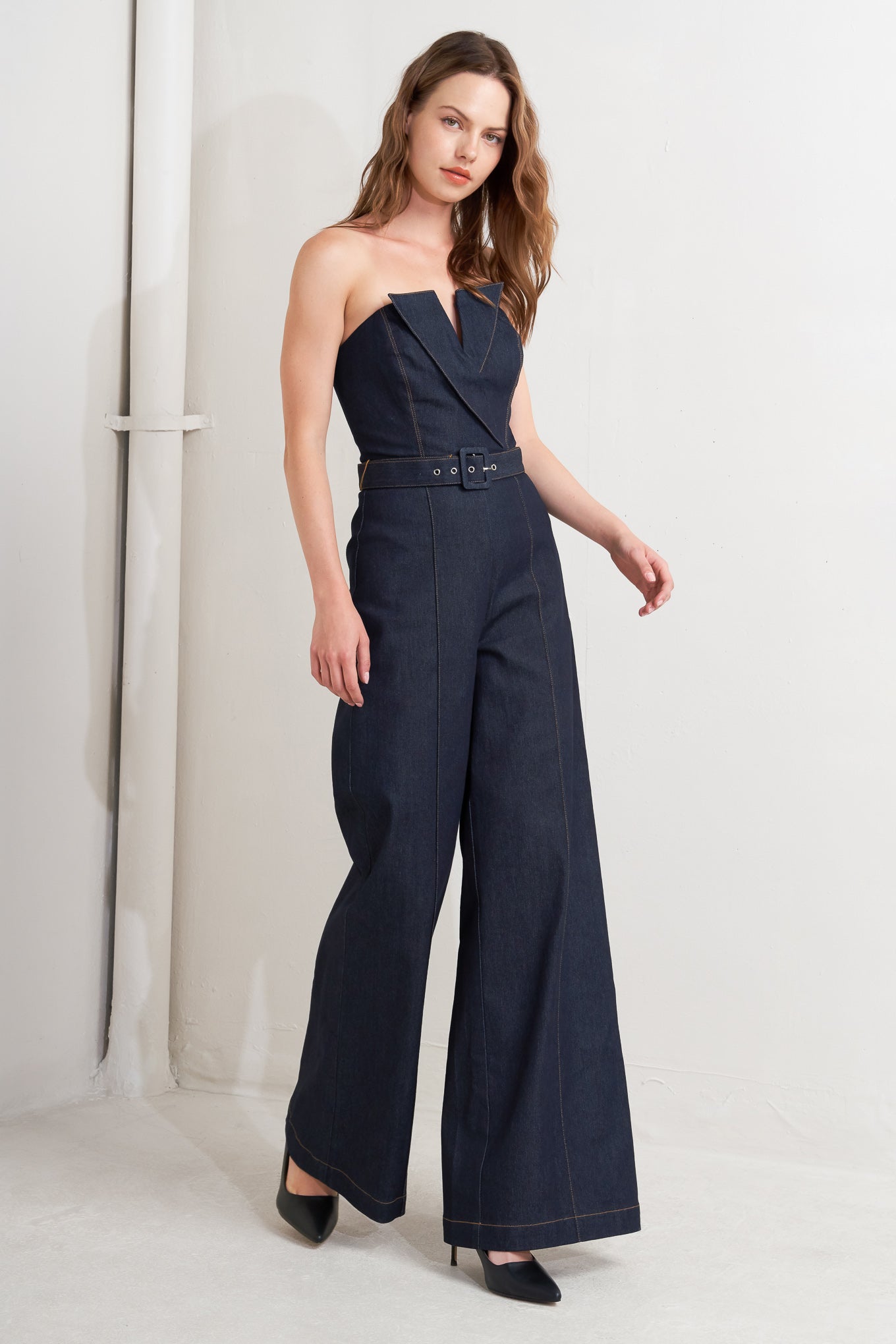 A denim jumpsuit featuring strapless, front fold over detail, self belt and wide leg