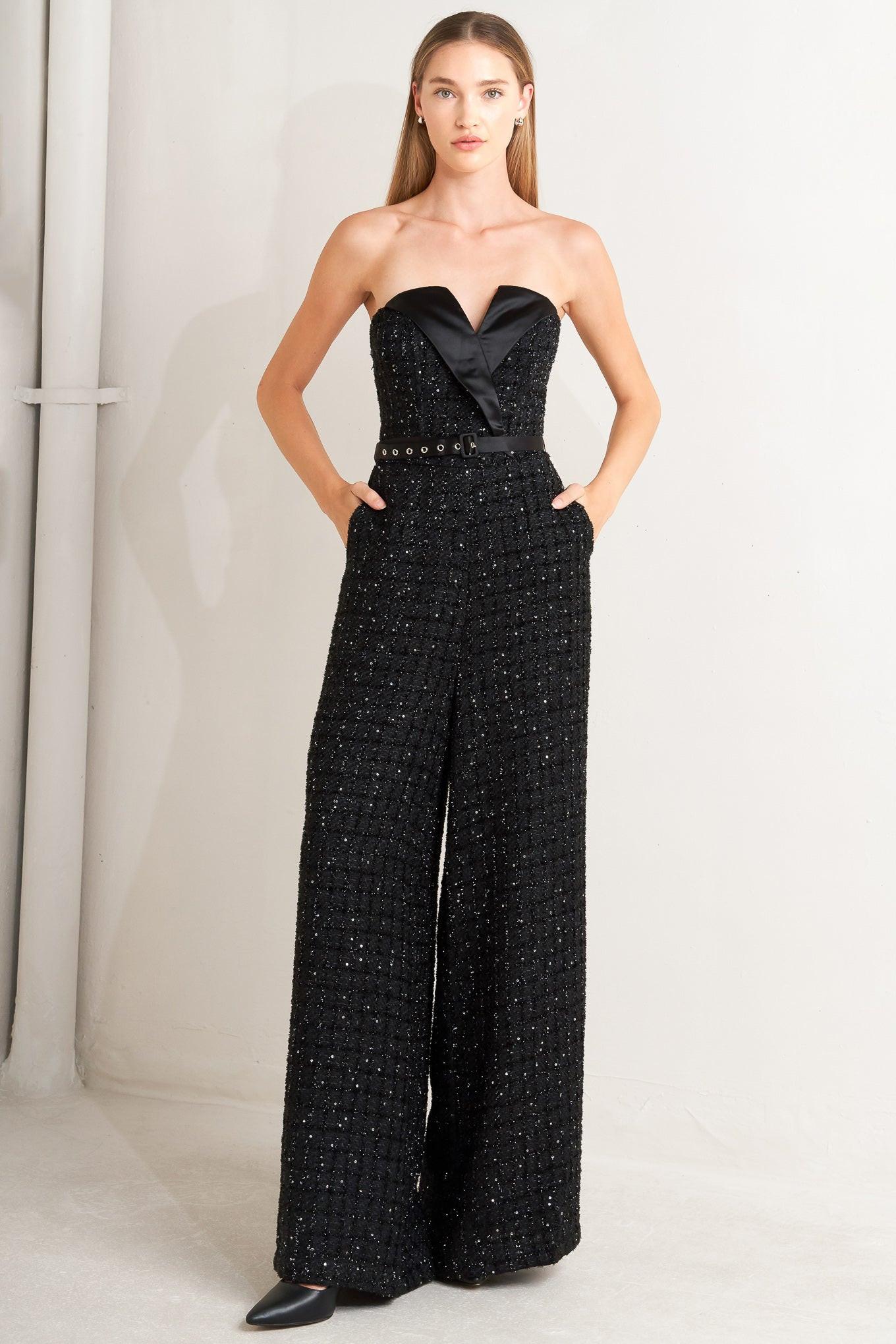 A woven tweed jumpsuit featuring strapless with V cut out, satin lapel, satin belt, wide leg and back zipper closure