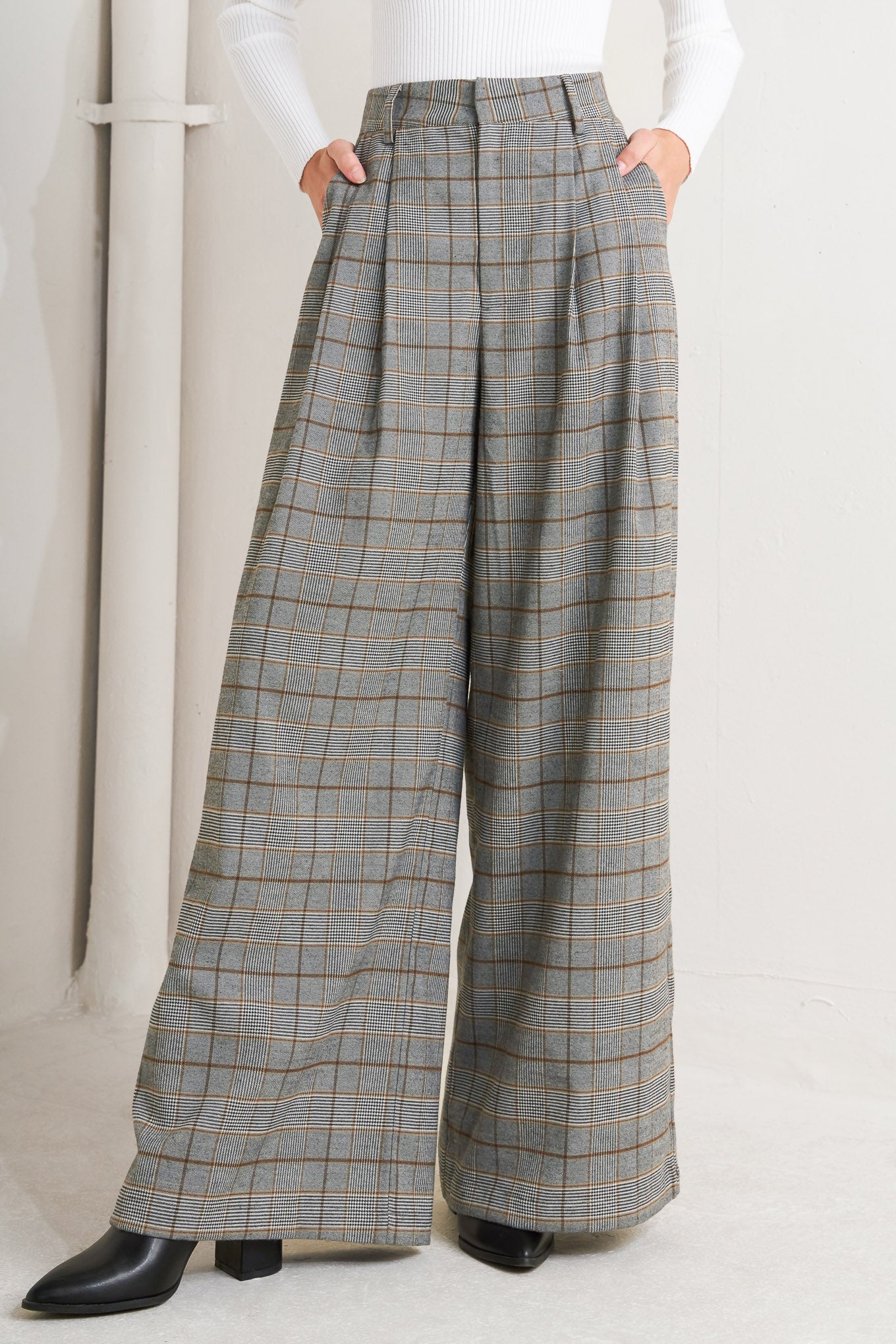 A woven plaid pant featuring front closure, side pockets and wide leg. 