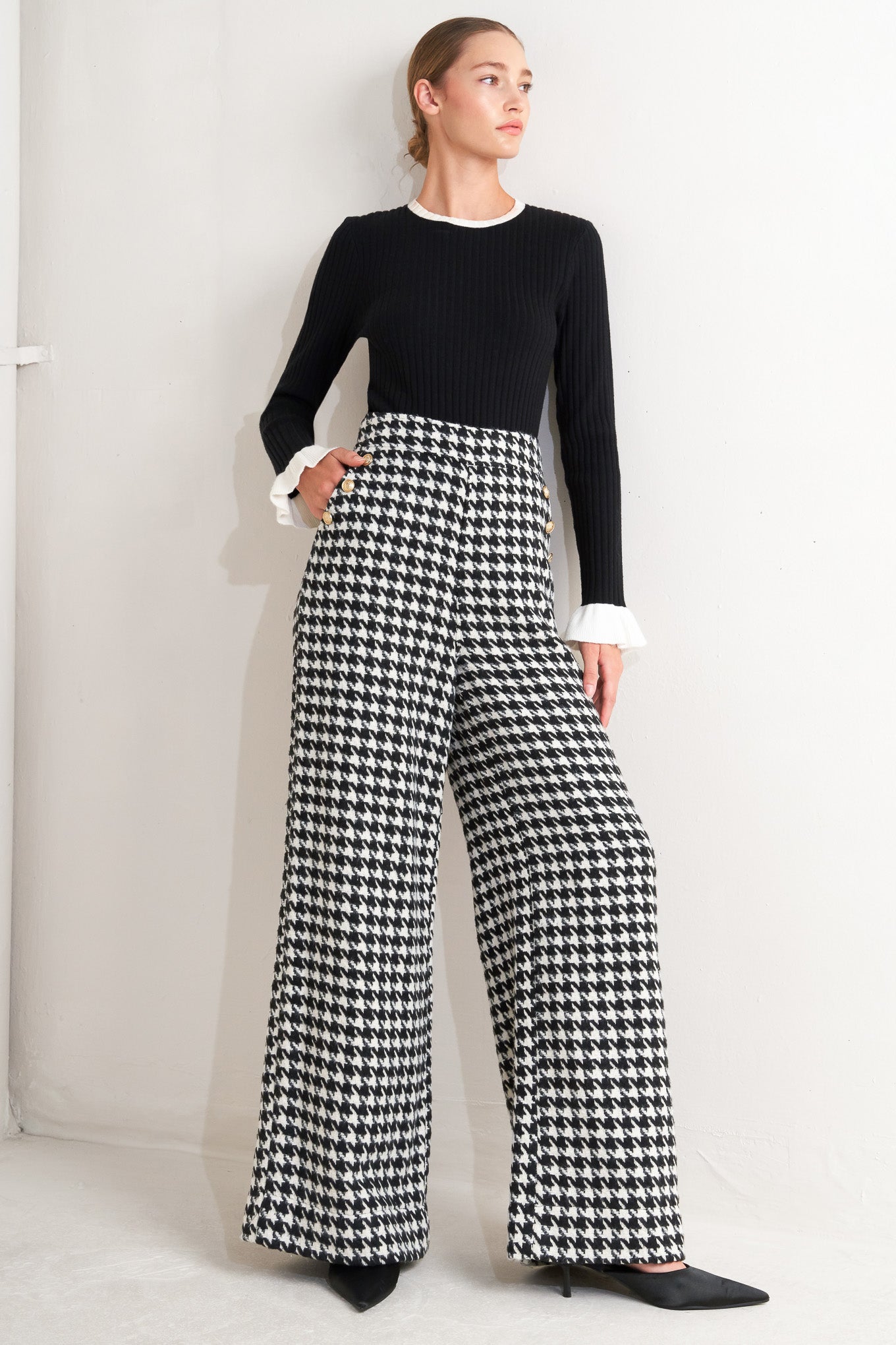 A woven houndstooth wide leg pant with side pockets with buttons and back zipper closure.