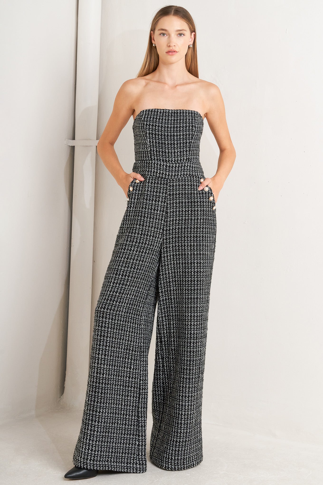 A tweed jumpsuit featuring strapless, side pockets with button detail, wide leg and back zipper closure